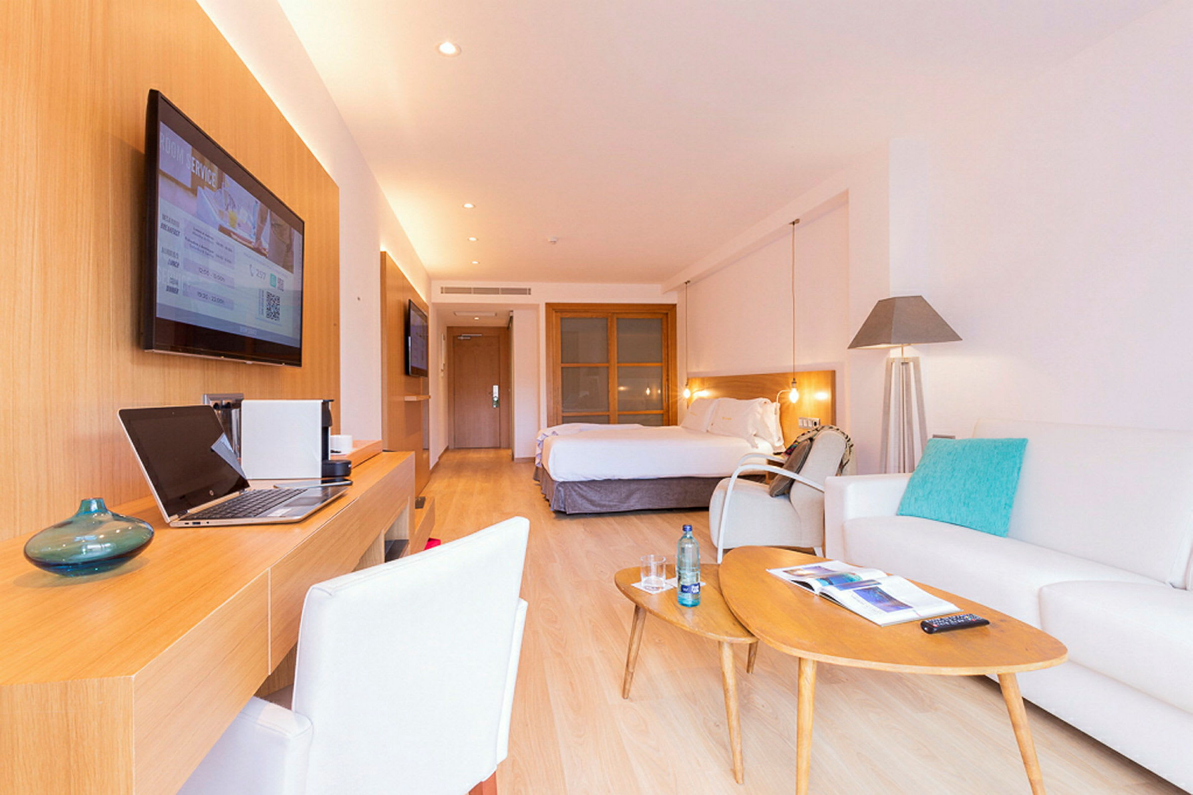 Et elegant hotelværelse med en stor seng, skrivebord, sofagruppe og moderne indretning. (AI-genereret tekst)