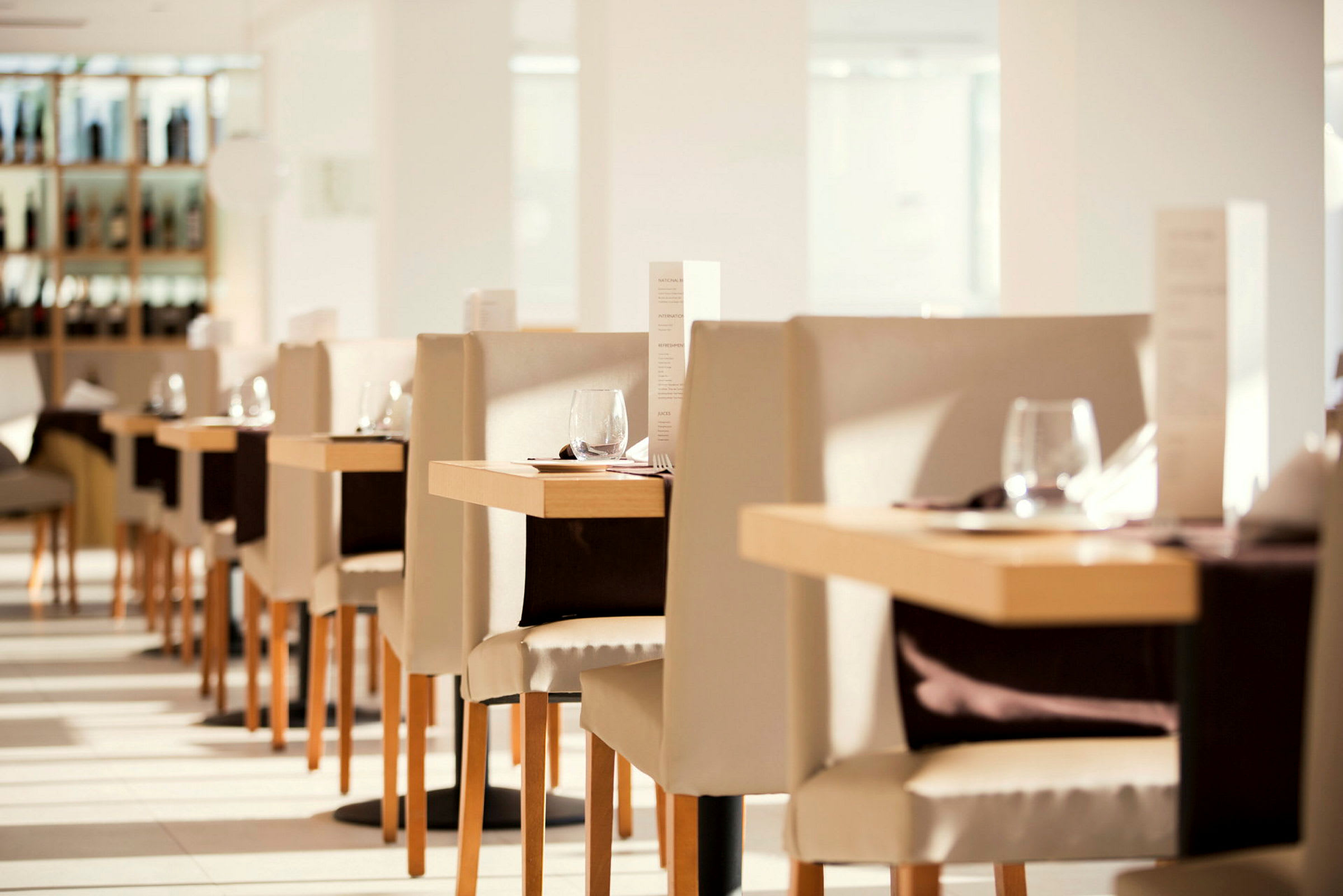 Interiør af en lys og elegant restaurant med dækkede borde og stole. (AI-genereret tekst)