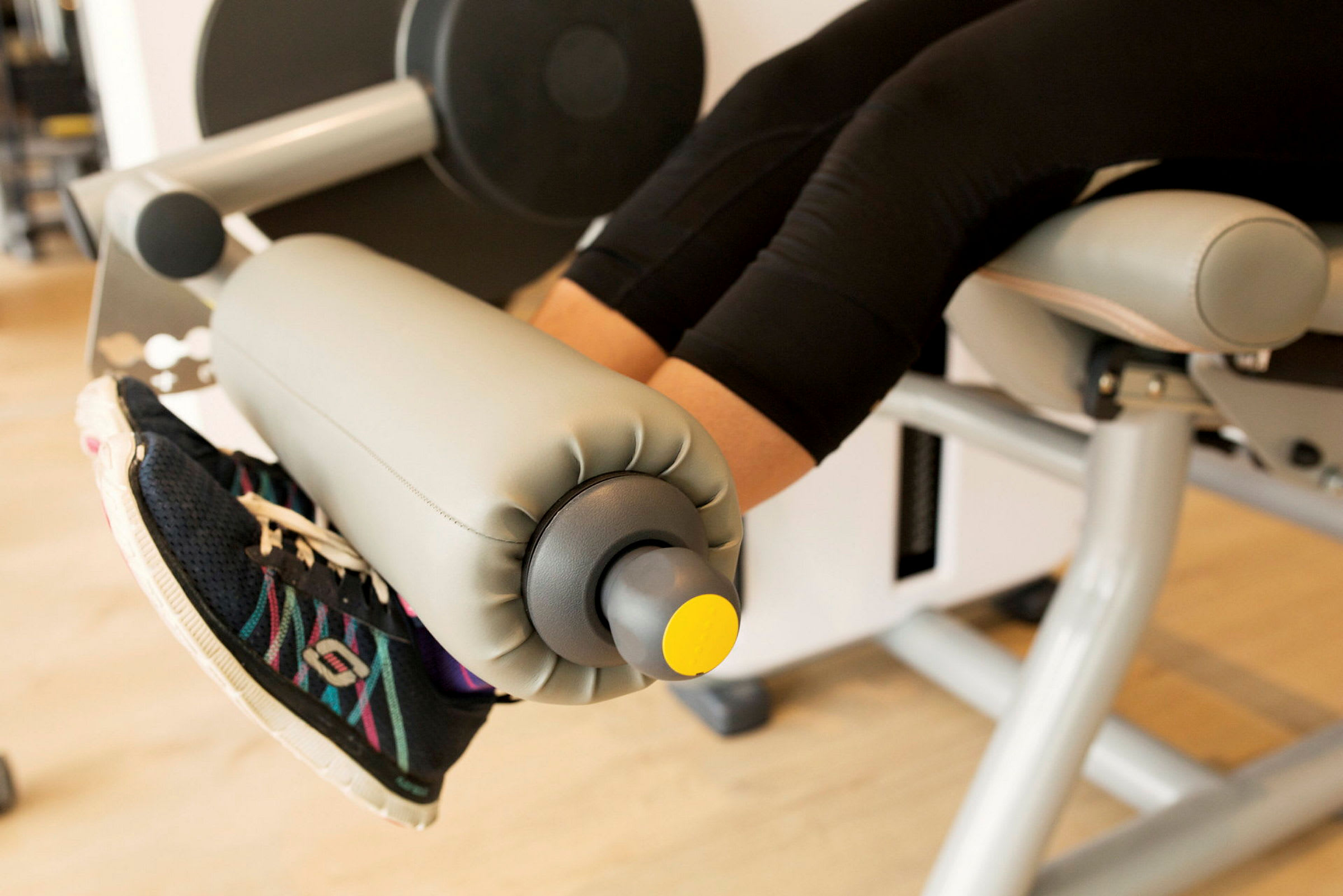 Billedet viser et par ben med træningssko, der bruger en bensparkmaskine i et fitnesscenter. (AI-genereret tekst)