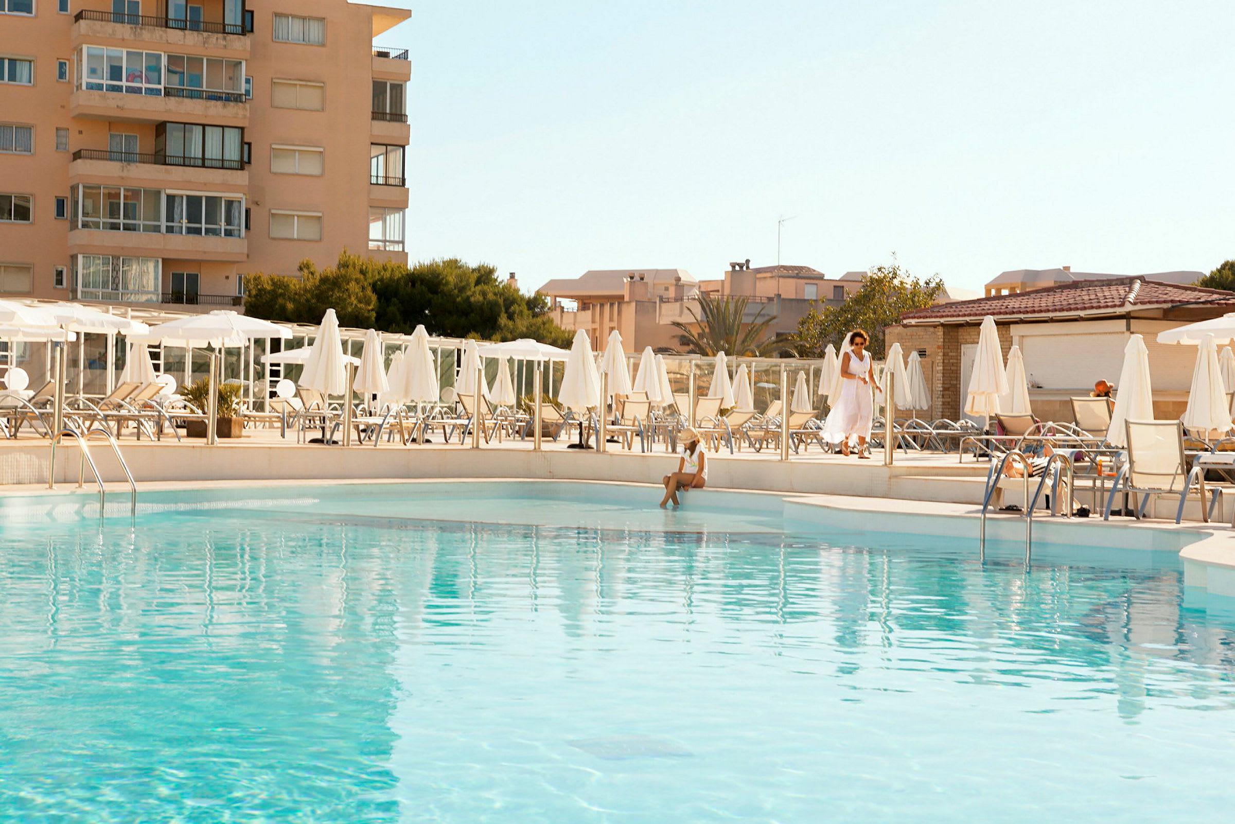 Udendørs pool ved hotel med omkringliggende solsenge og parasoller. (AI-genereret tekst)
