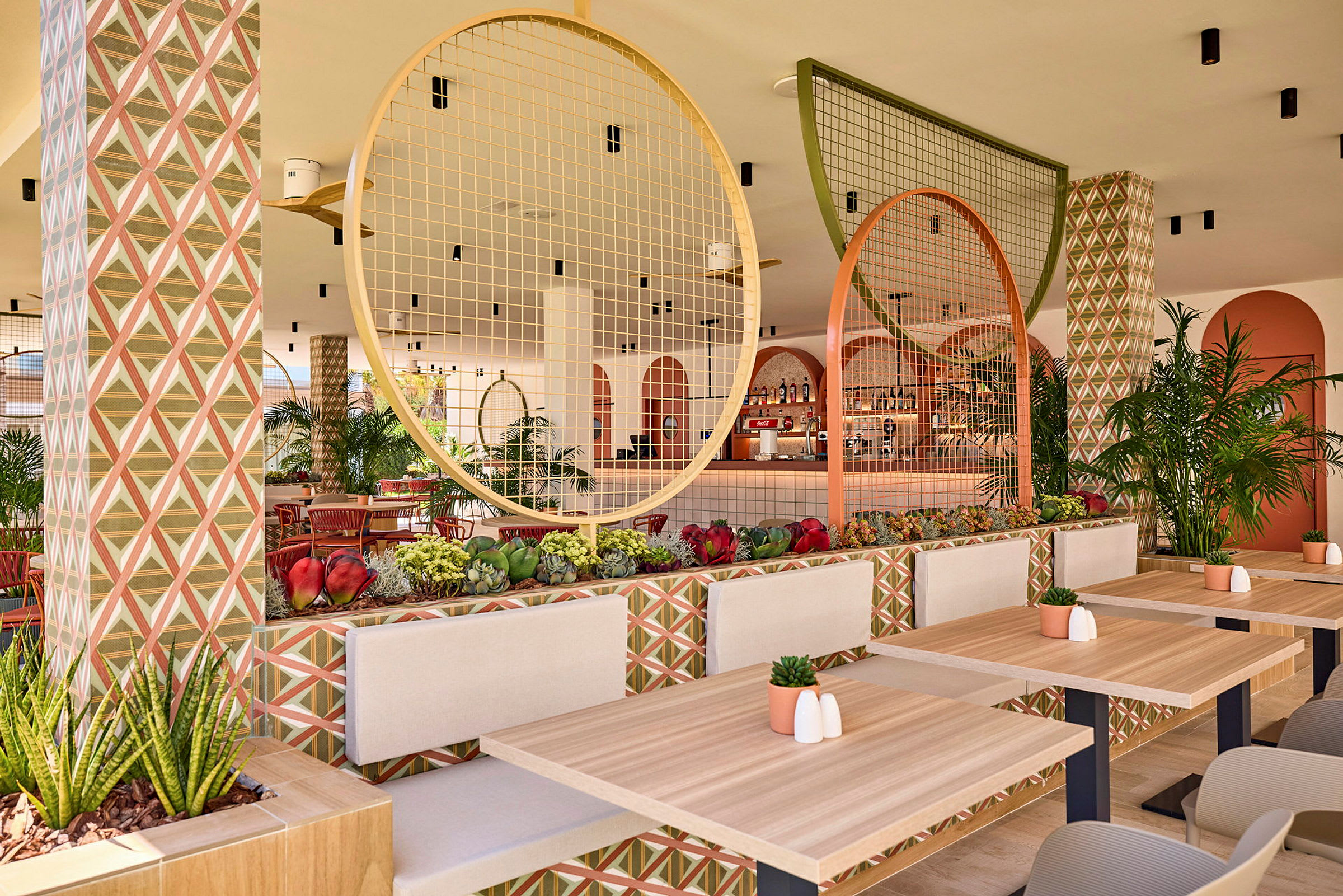 En velindrettet restaurant med træborde, geometrisk mønstrede vægge og dekorative cirkulære detaljer. (AI-genereret tekst)