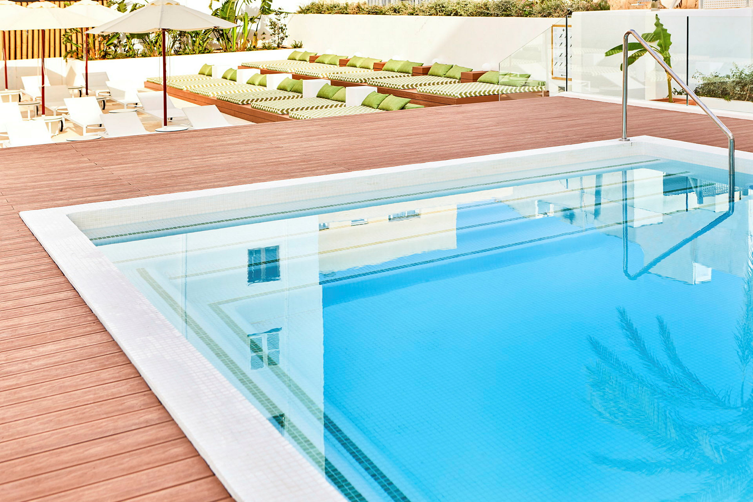 Udendørs swimmingpool med træterrasse og liggestole i baggrunden. (AI-genereret tekst)