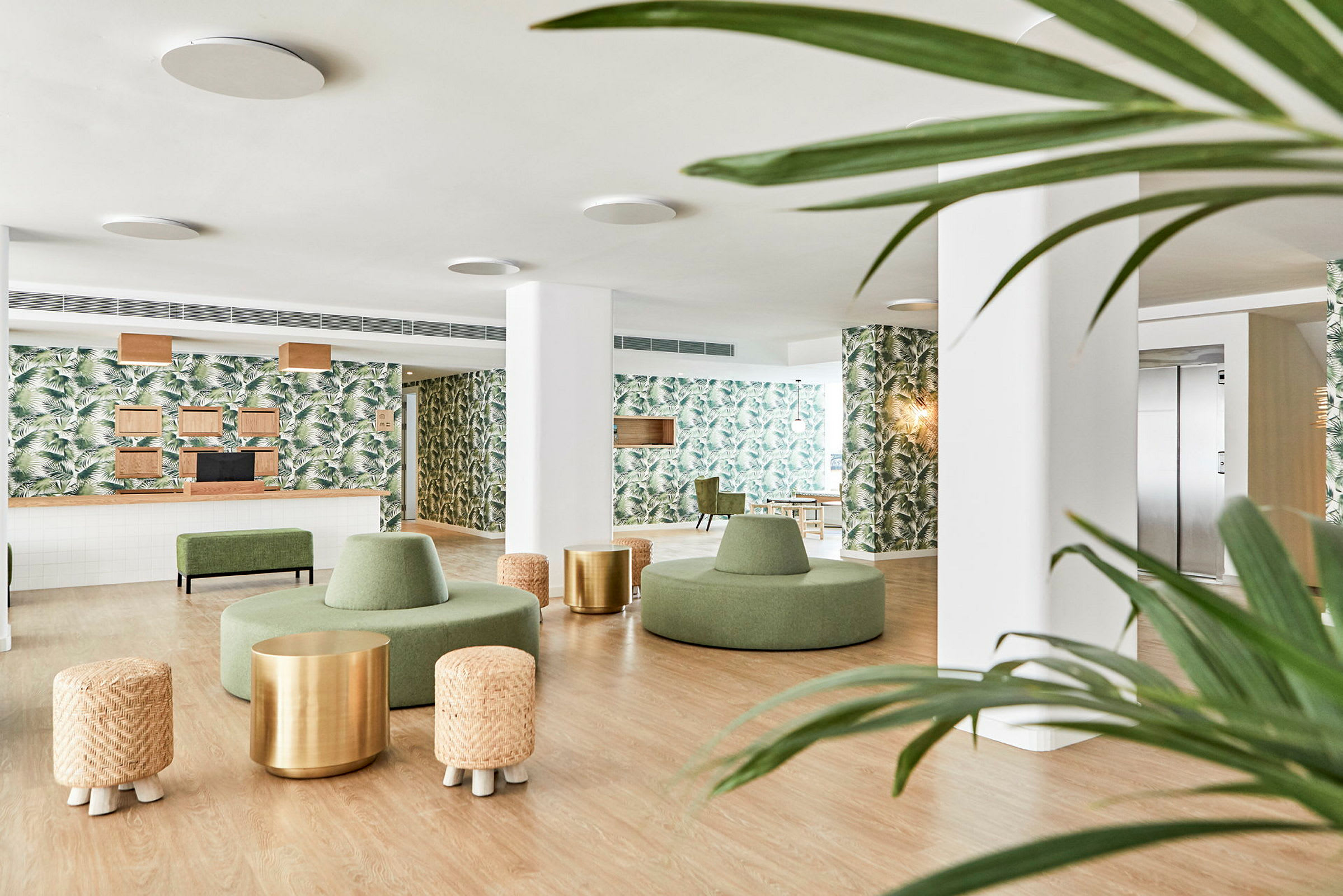 Moderne hotellobby med grønne møbler, vægge dekoreret med palmebladsmønstre og trædetaljer. (AI-genereret tekst)