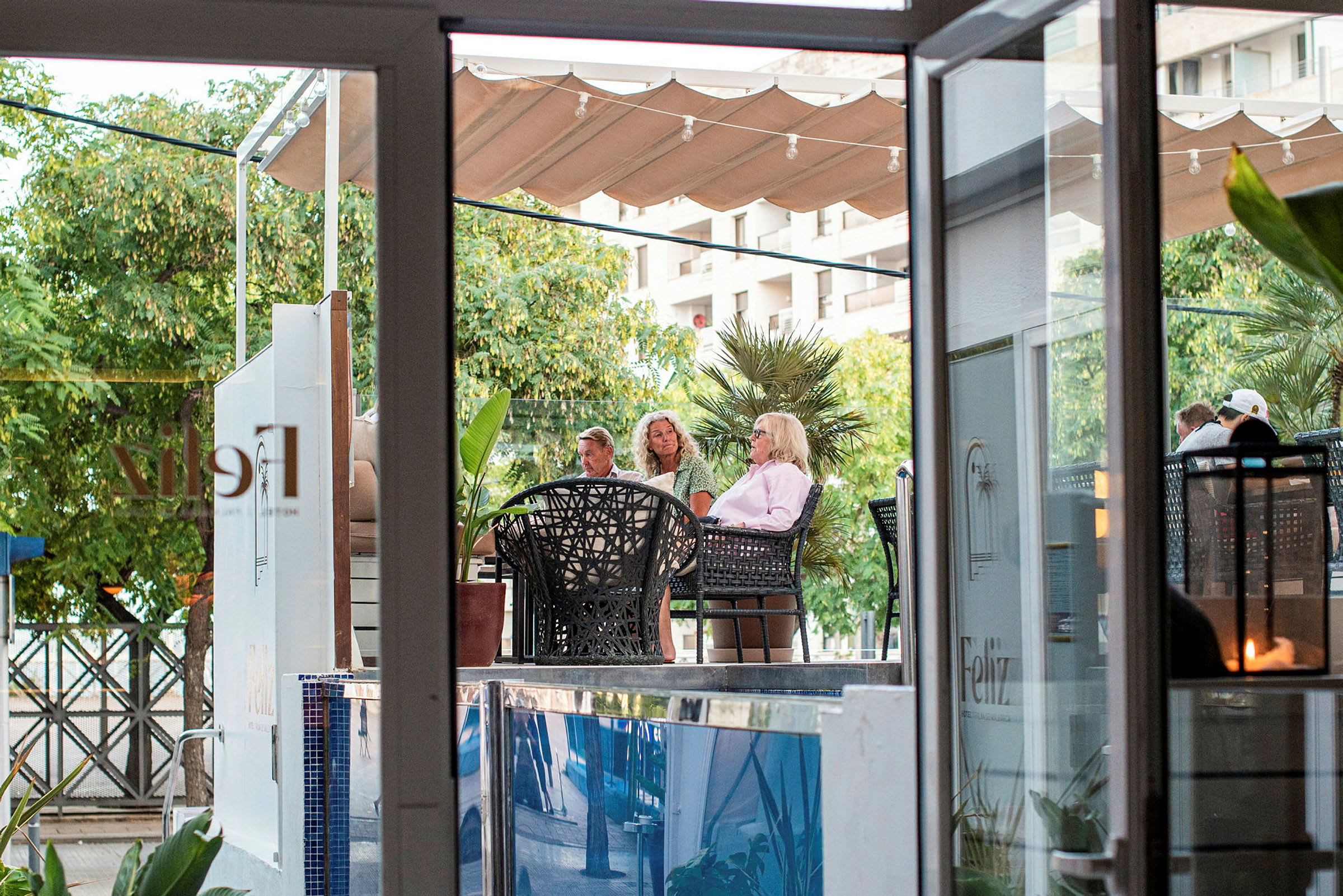 Personer sidder på en udendørs café i grønne omgivelser. (AI-genereret tekst)