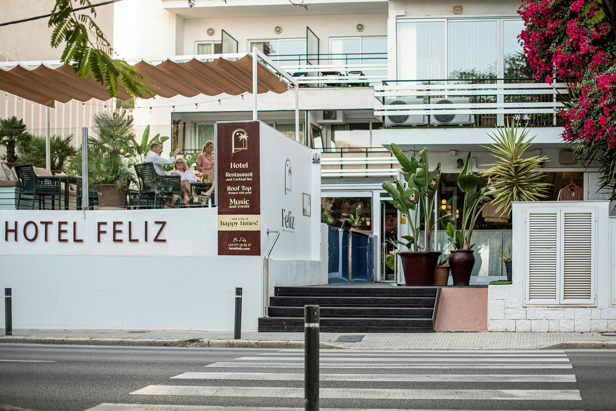 Hotel Feliz med udendørs serveringsområde og blomstrende vegetation. (AI-genereret tekst)