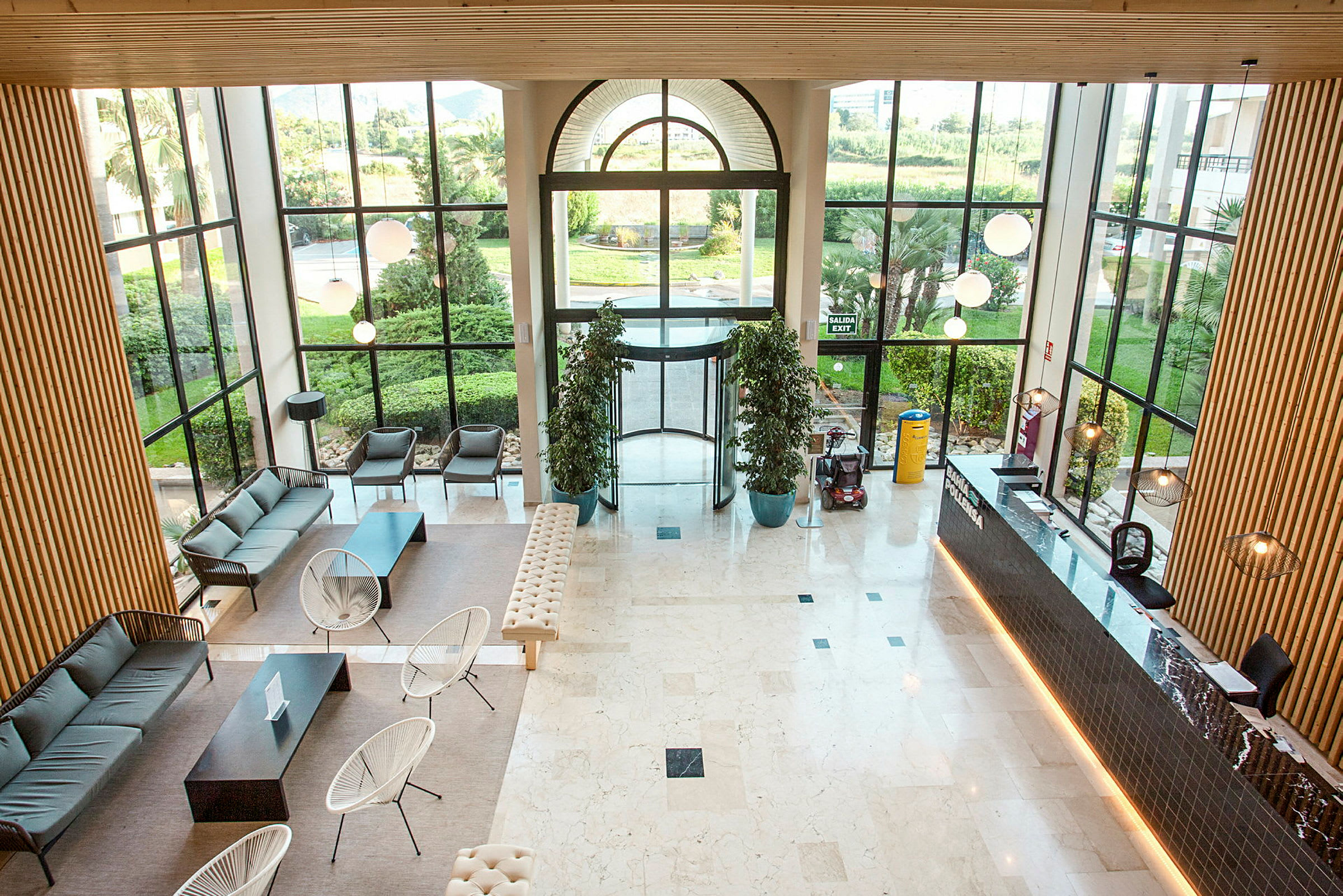En moderne hotellobby med siddepladser, receptionsskrank og store vinduer, der tillader naturligt lys at strømme ind. (AI-genereret tekst)