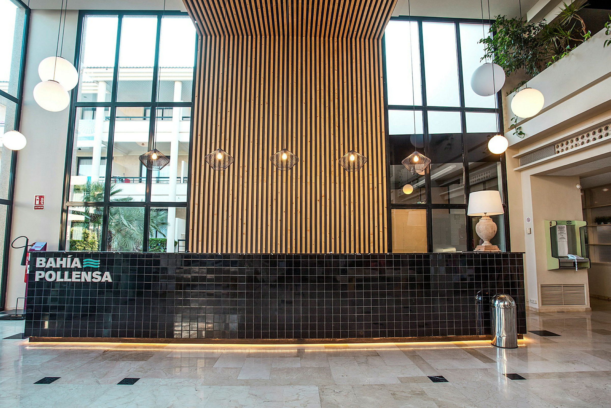 Receptionen på et hotel med en moderne indretning, en sort flisebelagt skranke og en væg af træ bagved. (AI-genereret tekst)