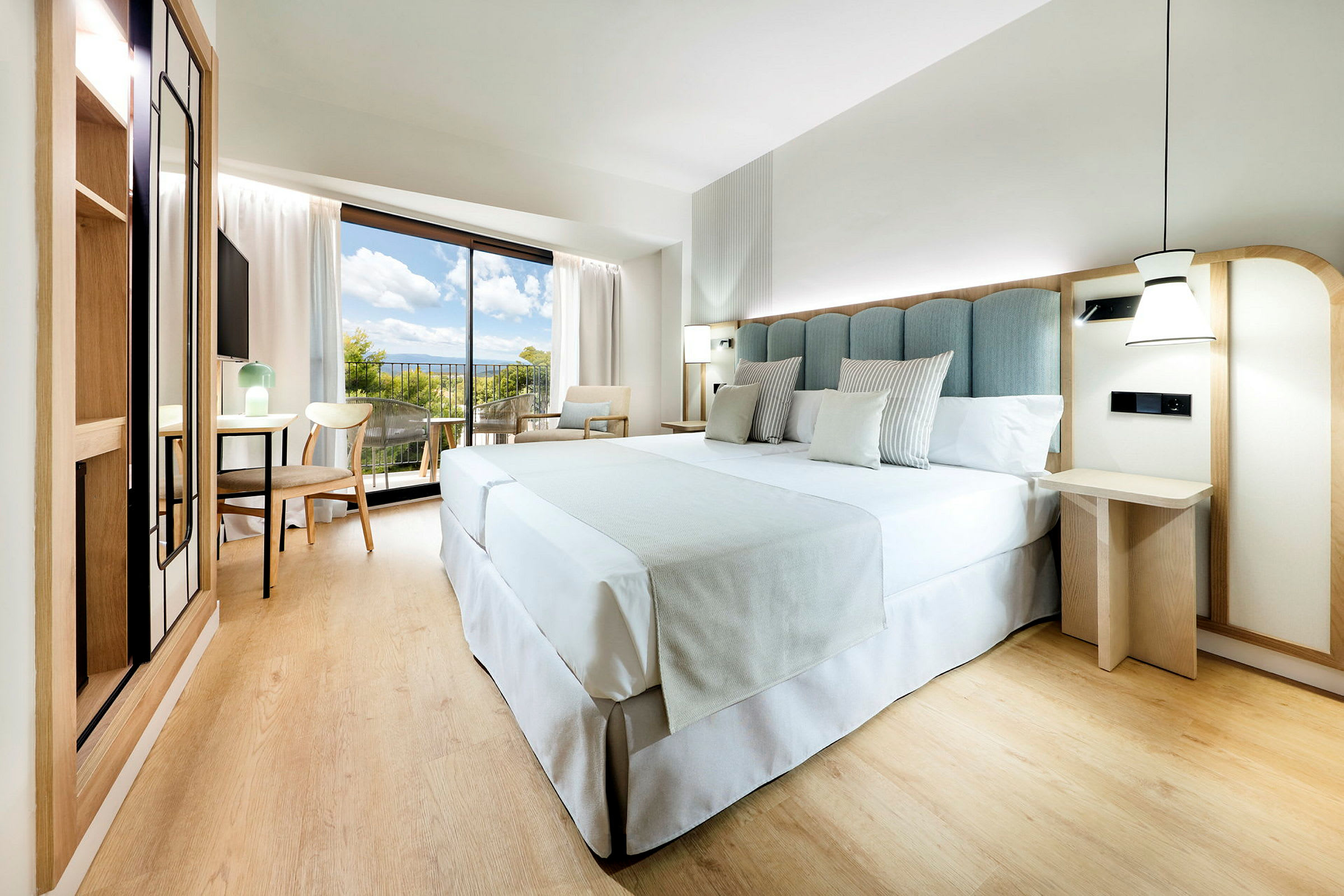 Et moderne hotelværelse med en stor seng, træmøbler og en balkon med udsigt. (AI-genereret tekst)