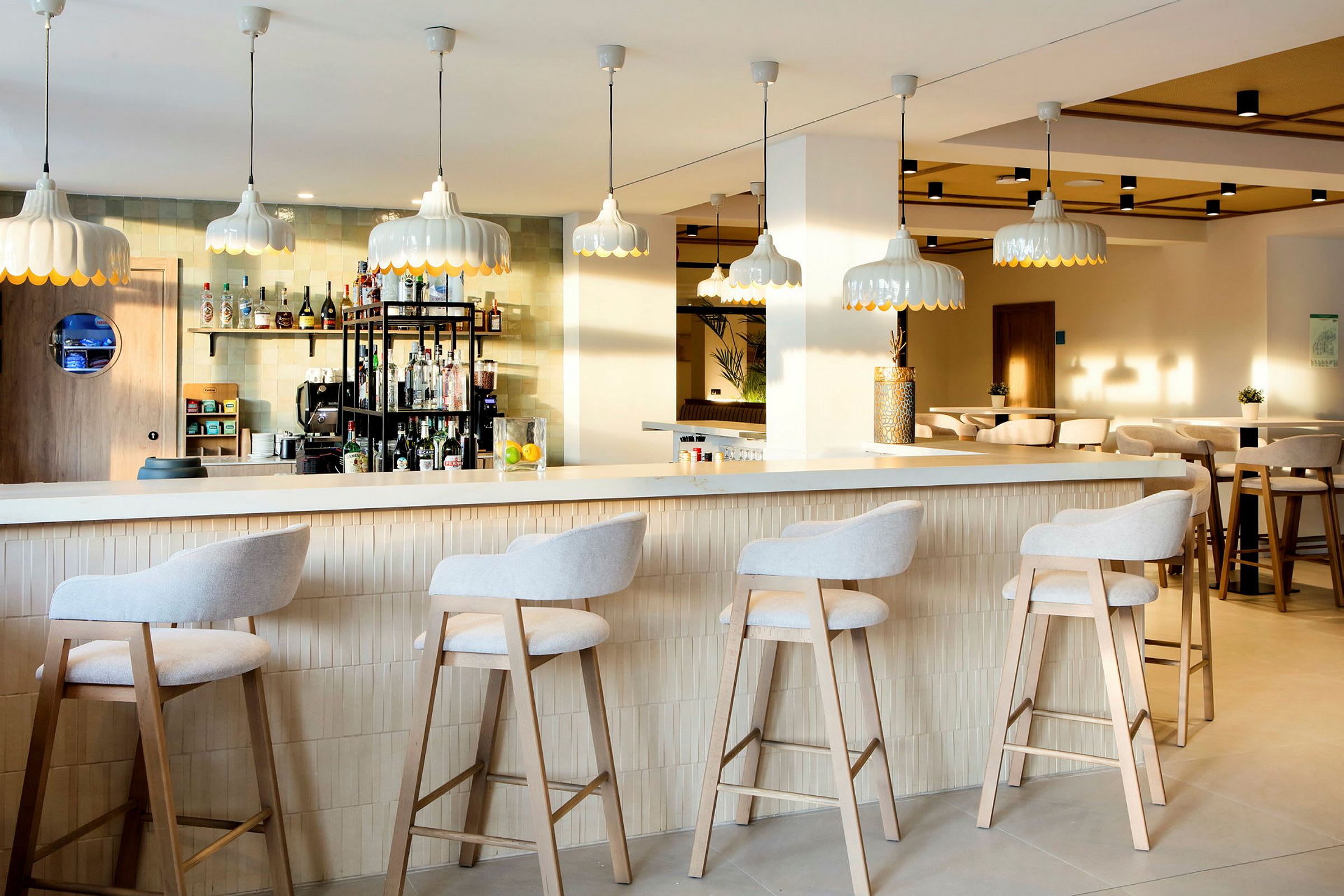 En moderne bar med høje stole ved disken og stilfulde lamper hængende fra loftet. (AI-genereret tekst)