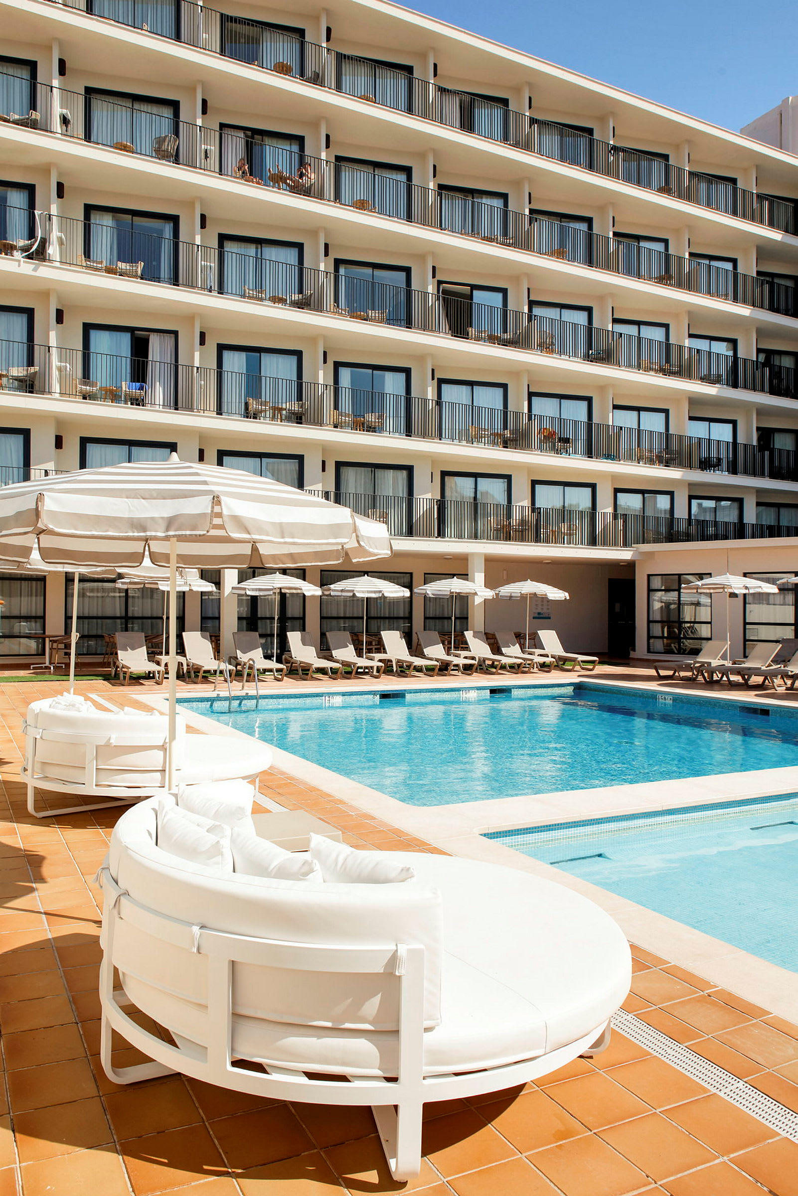 Udendørs pool ved et hotel med liggestole og parasoller. (AI-genereret tekst)