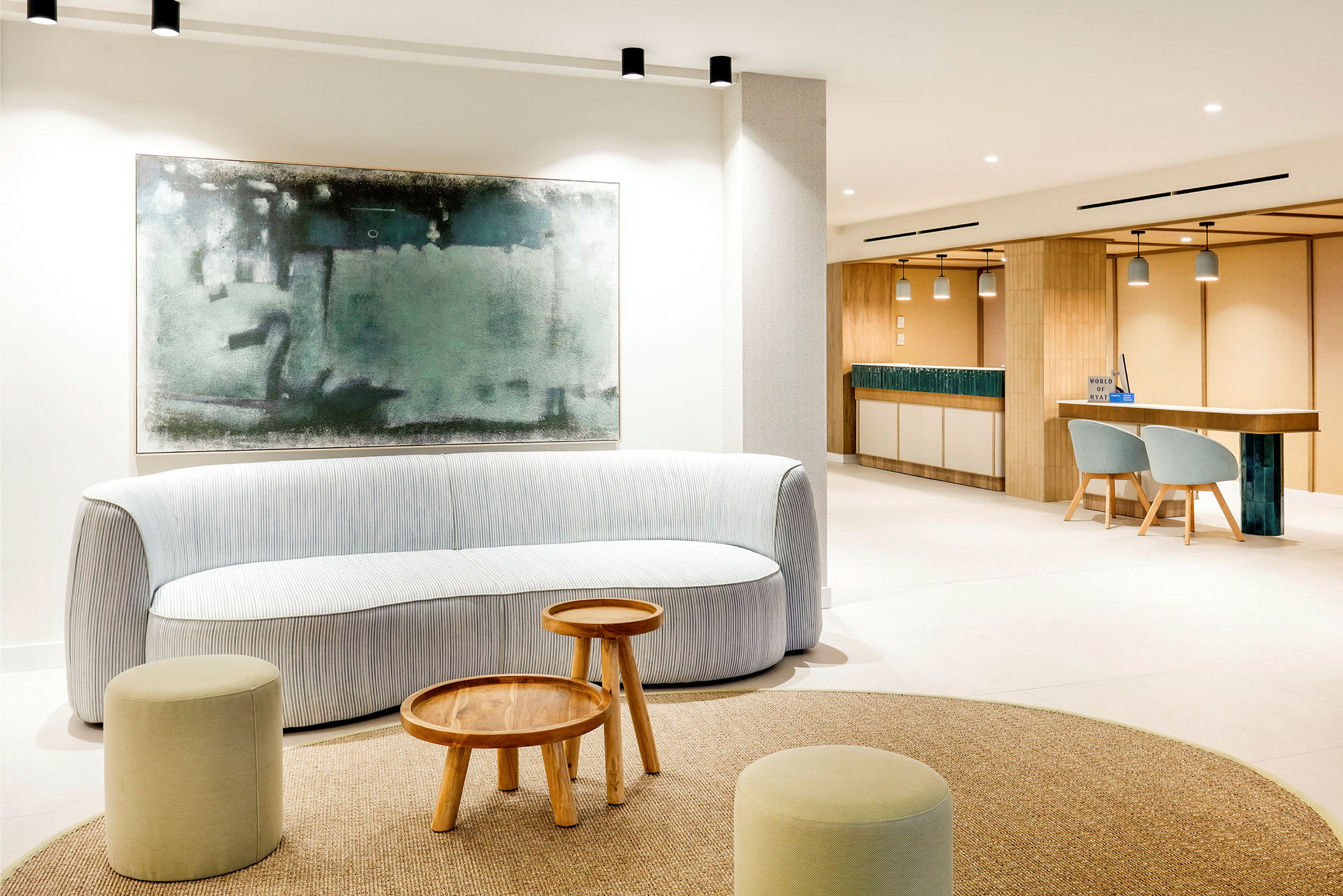 En lys, moderne lounge med en sofa, små træborde og skamler. Et stort abstrakt billede hænger på væggen bag sofaen. (AI-genereret tekst)