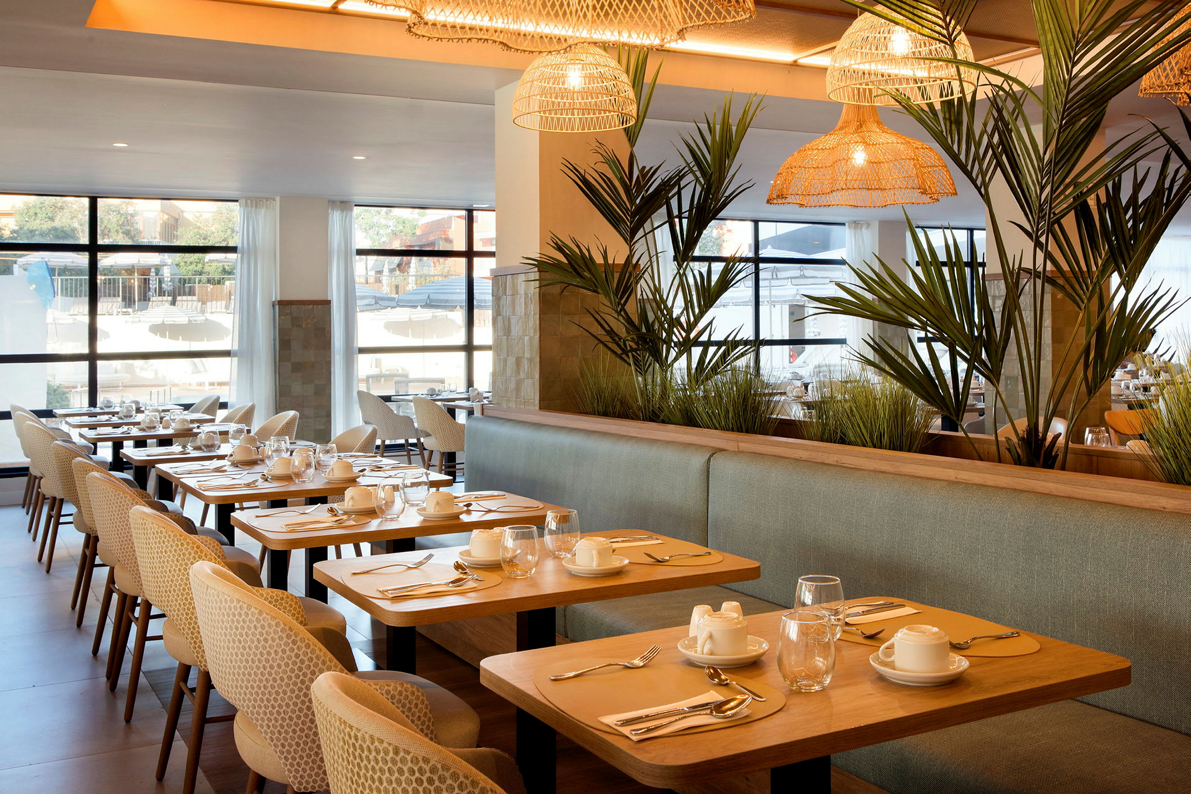 En elegant restaurant med dækkede borde, komfortable stole og grønne planter som dekoration. (AI-genereret tekst)