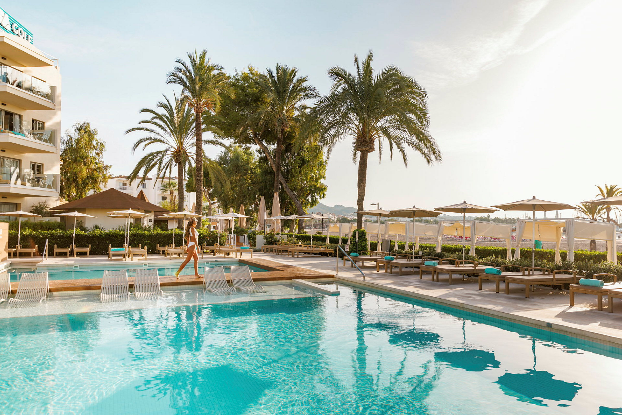 En swimmingpool med liggestole og parasoller på et hotelområde. (AI-genereret tekst)
