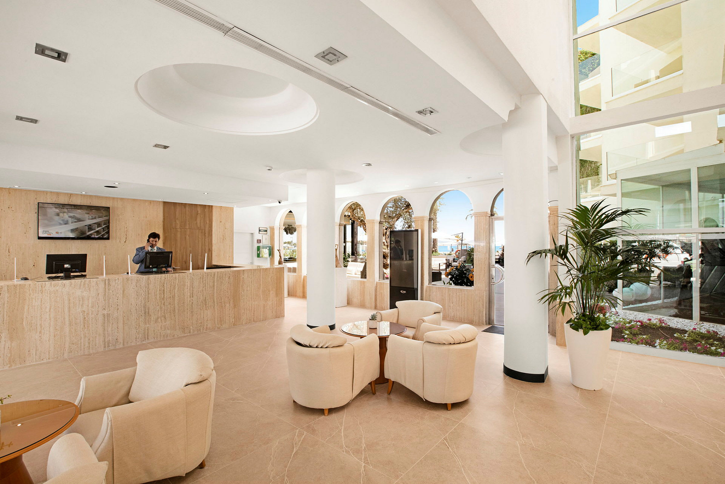 Lys hotelreception med siddegruppe og udsigt mod en solrig terrasse. (AI-genereret tekst)