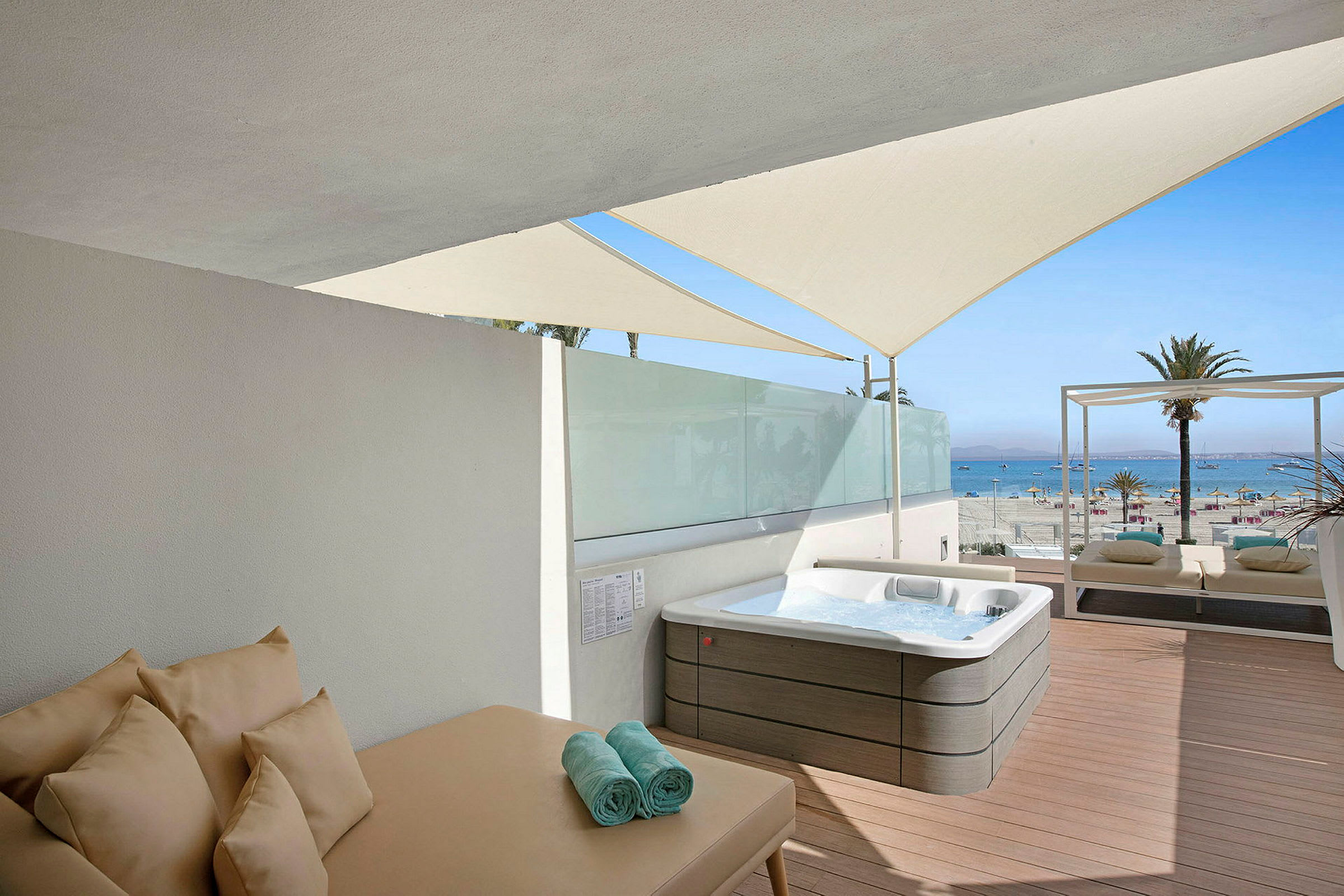 En solterrasse med en jacuzzi, solseng og udsigt til stranden og havet. (AI-genereret tekst)
