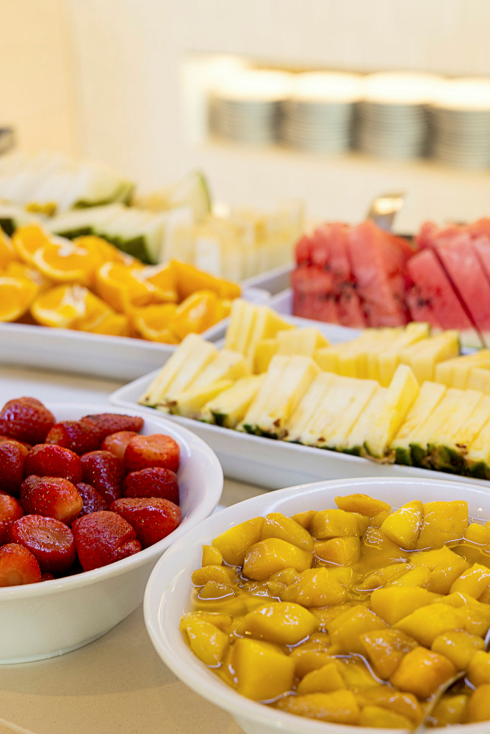 Opskåret frugt, inklusive jordbær, mango, melon og ananas, serveret i hvide skåle. (AI-genereret tekst)