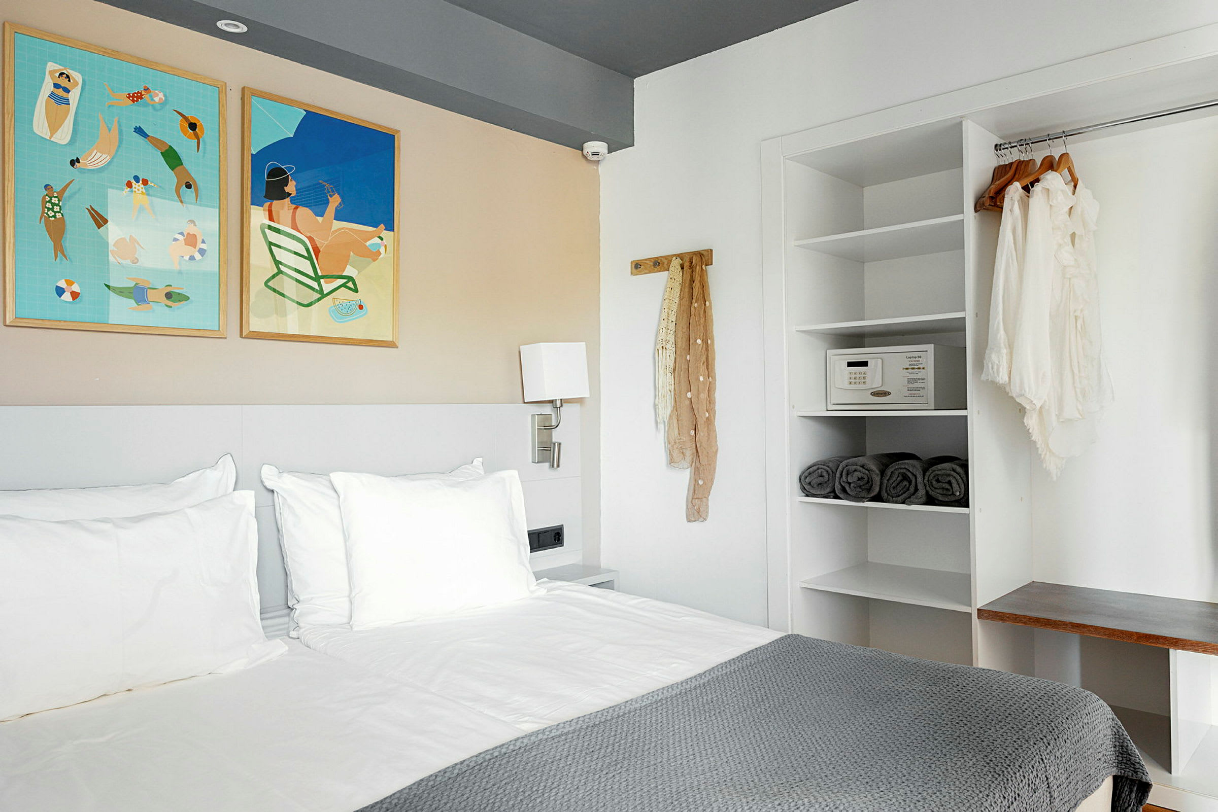 Et moderne hotelværelse med en seng, væghængte malerier og et åbent garderobeskab. (AI-genereret tekst)
