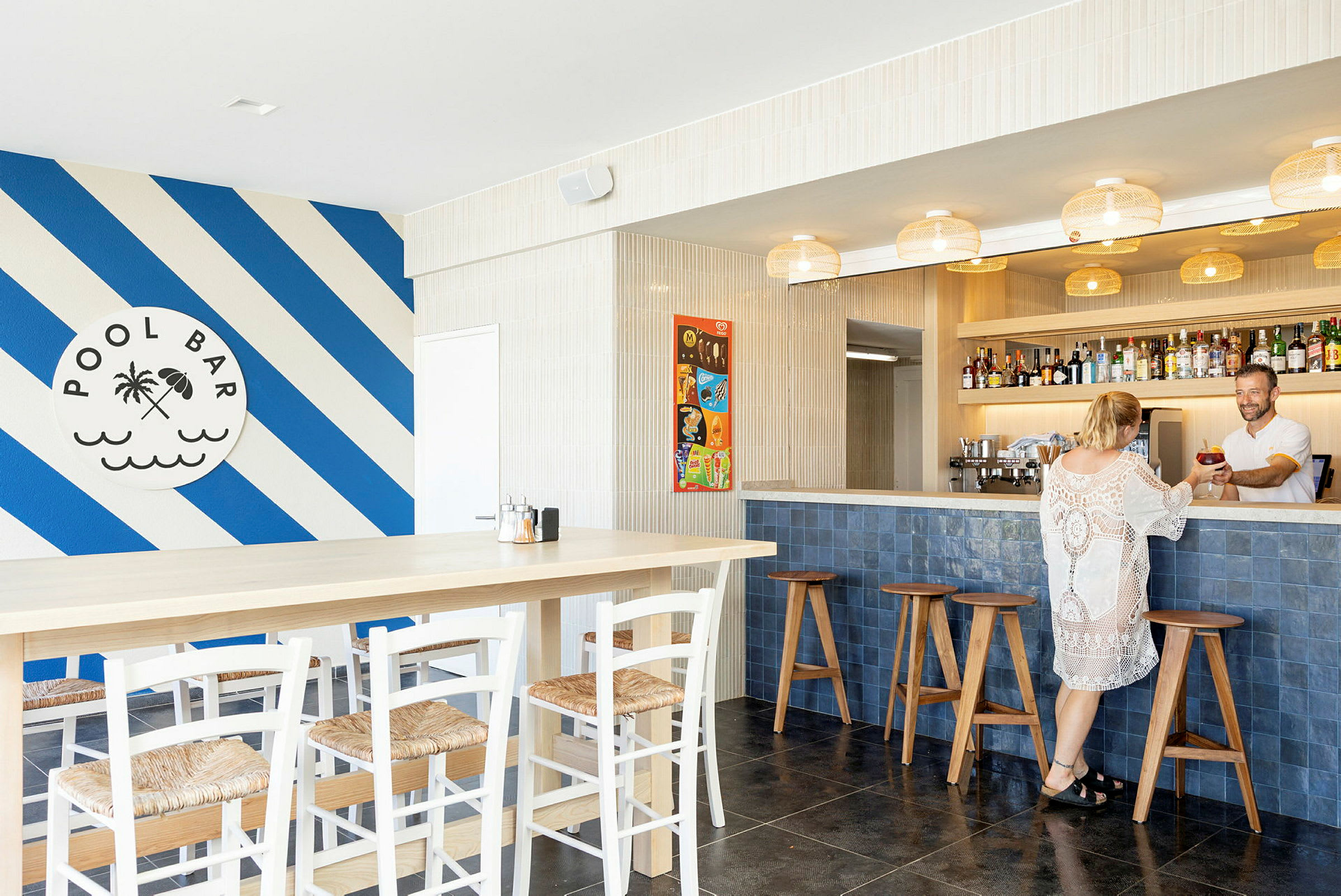 Billede af en poolbar med blå og hvide diagonale striber på væggen og siddepladser ved bardisken og bordene. (AI-genereret tekst)