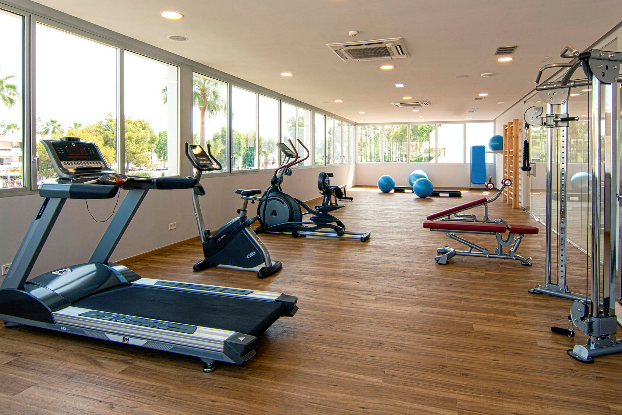 Et rummeligt fitnesscenter med træningsmaskiner, frie vægte og pilatesbolde. (AI-genereret tekst)