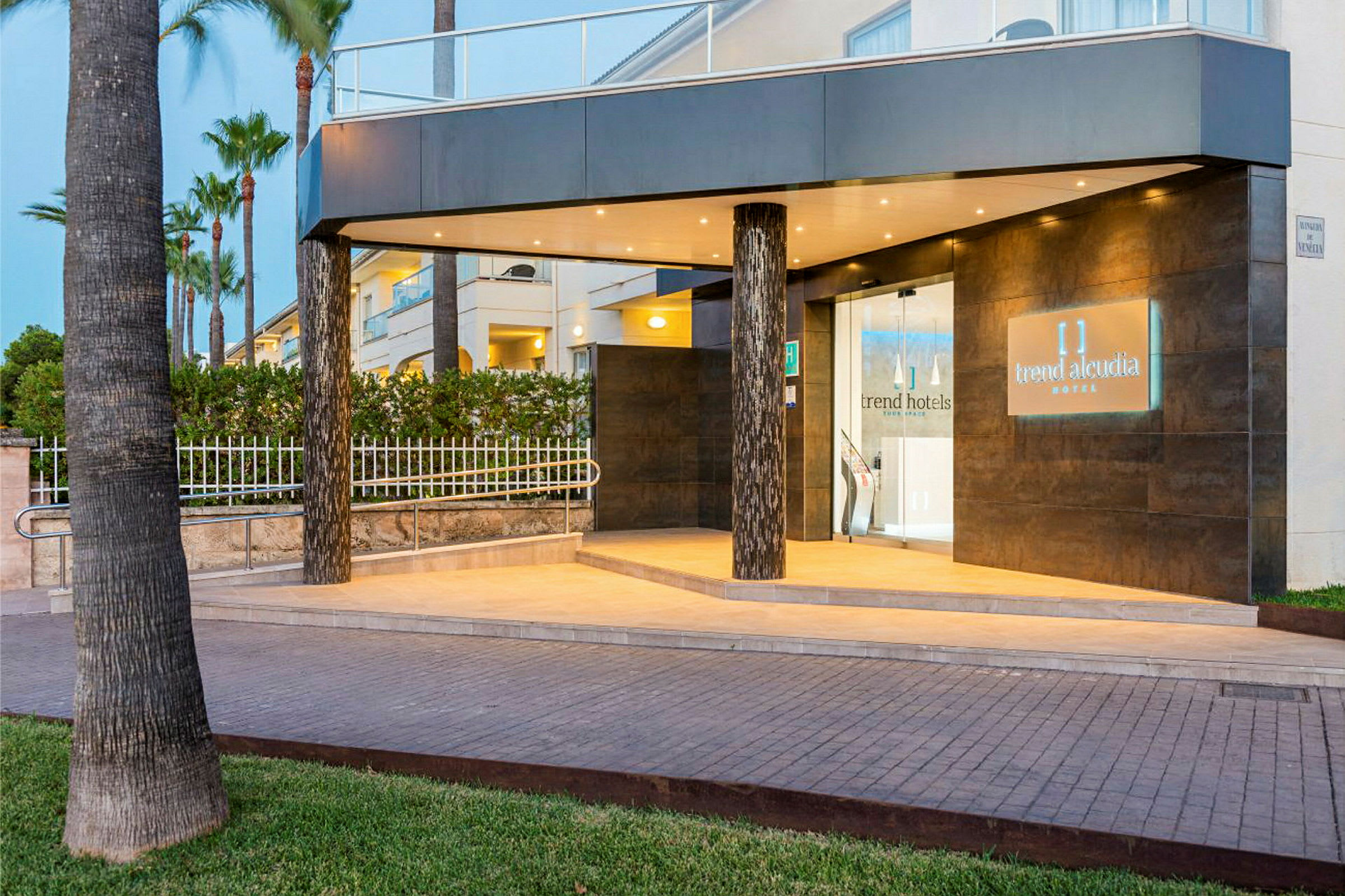 Indgangen til et hotel med belysning og navnet 'Trend Alcudia Hotel' på et skilt. (AI-genereret tekst)