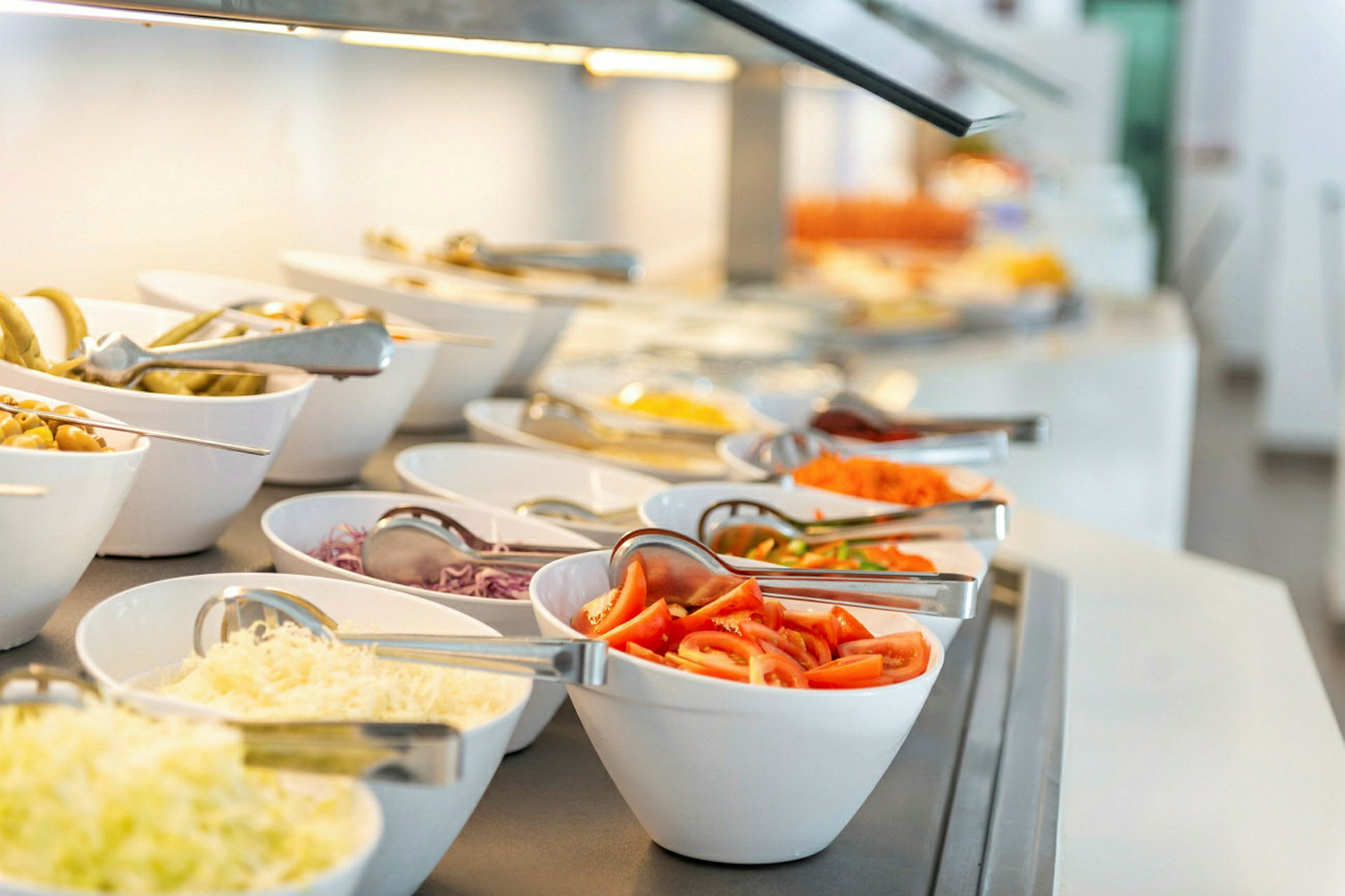 Buffet med forskellige salatingredienser i hvide skåle. (AI-genereret tekst)