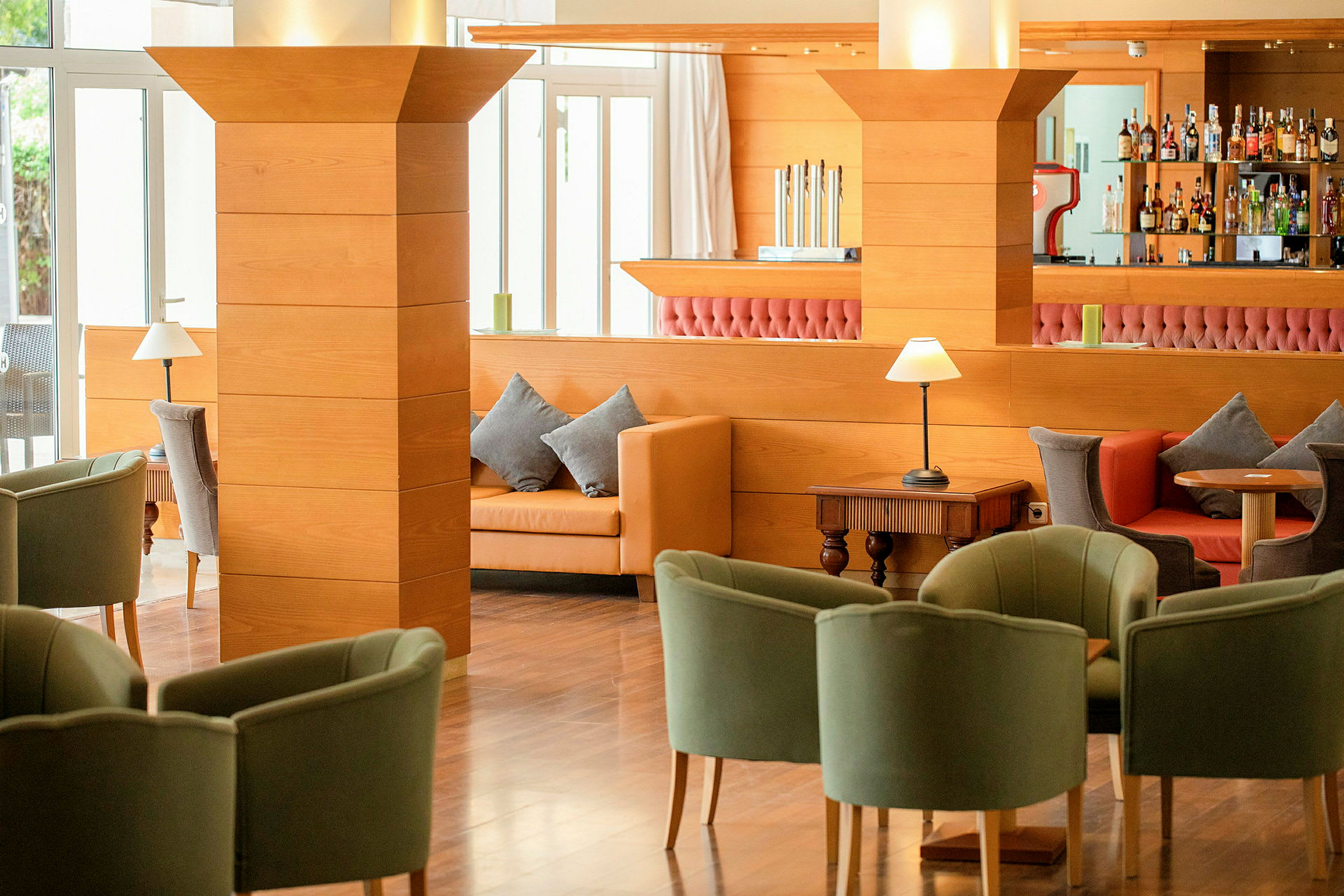 Interiør af en hotellounge med komfortable siddepladser, træinteriør og en bar i baggrunden. (AI-genereret tekst)