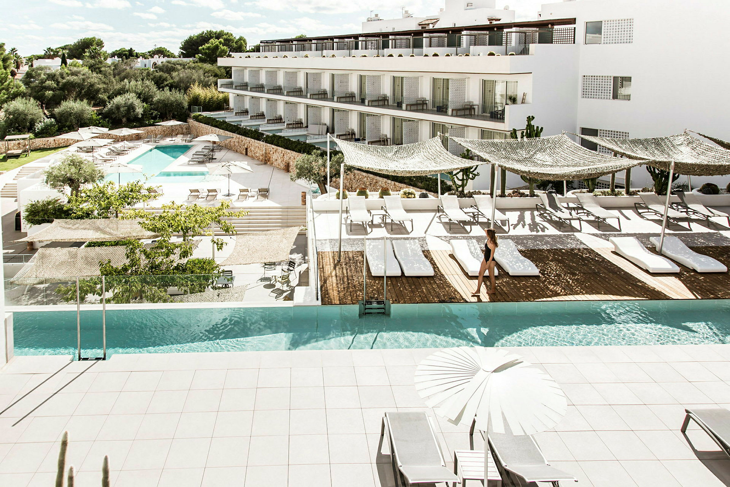 En moderne hotelpool med liggestole og parasoller på en solrig terrasse. (AI-genereret tekst)