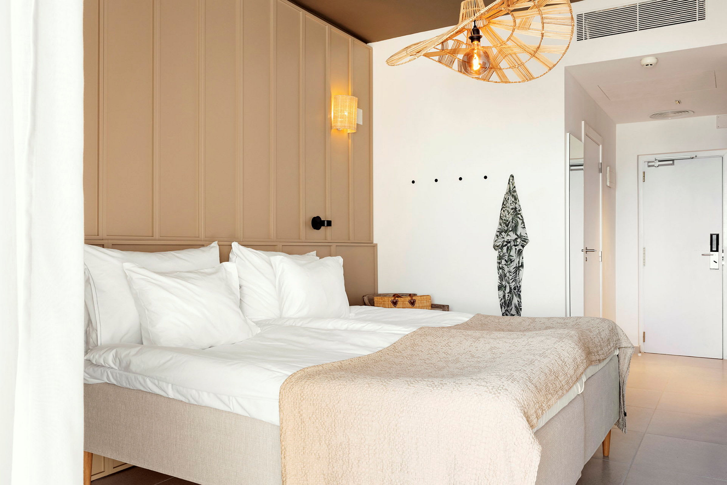 Et hotelværelse med en dobbeltseng, hvide vægge og lys indretning. (AI-genereret tekst)