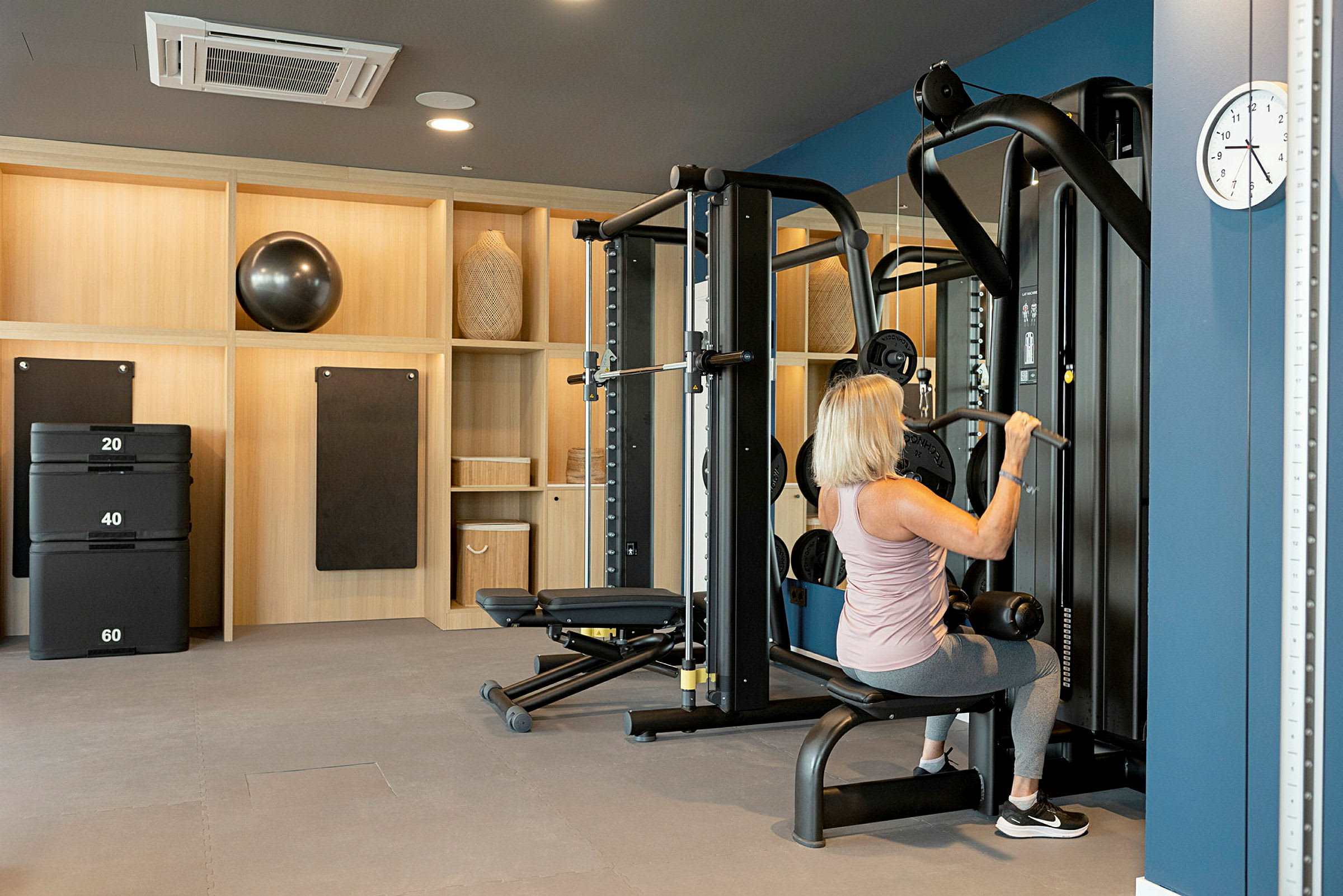 En person bruger træningsudstyr i et fitnessrum. (AI-genereret tekst)