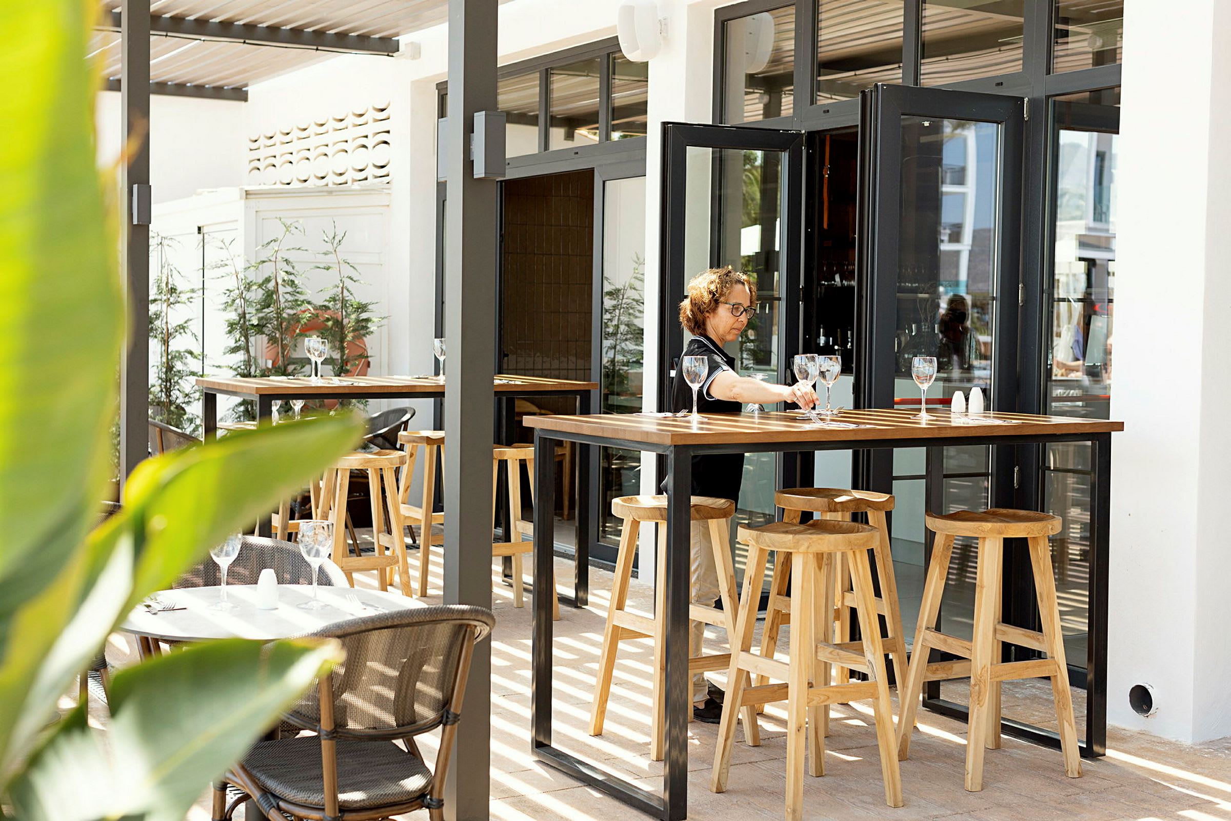 En udendørs restaurant med borde og høje træskamler. (AI-genereret tekst)
