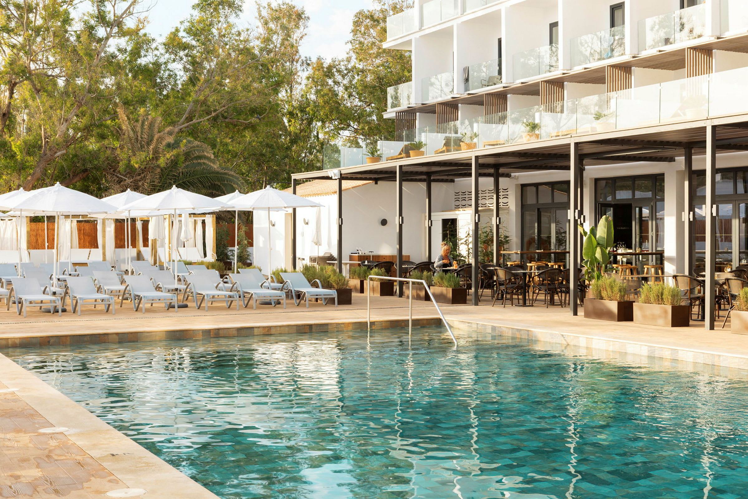 Udendørs swimmingpool omkranset af liggestole og parasoller ved et hotel. (AI-genereret tekst)