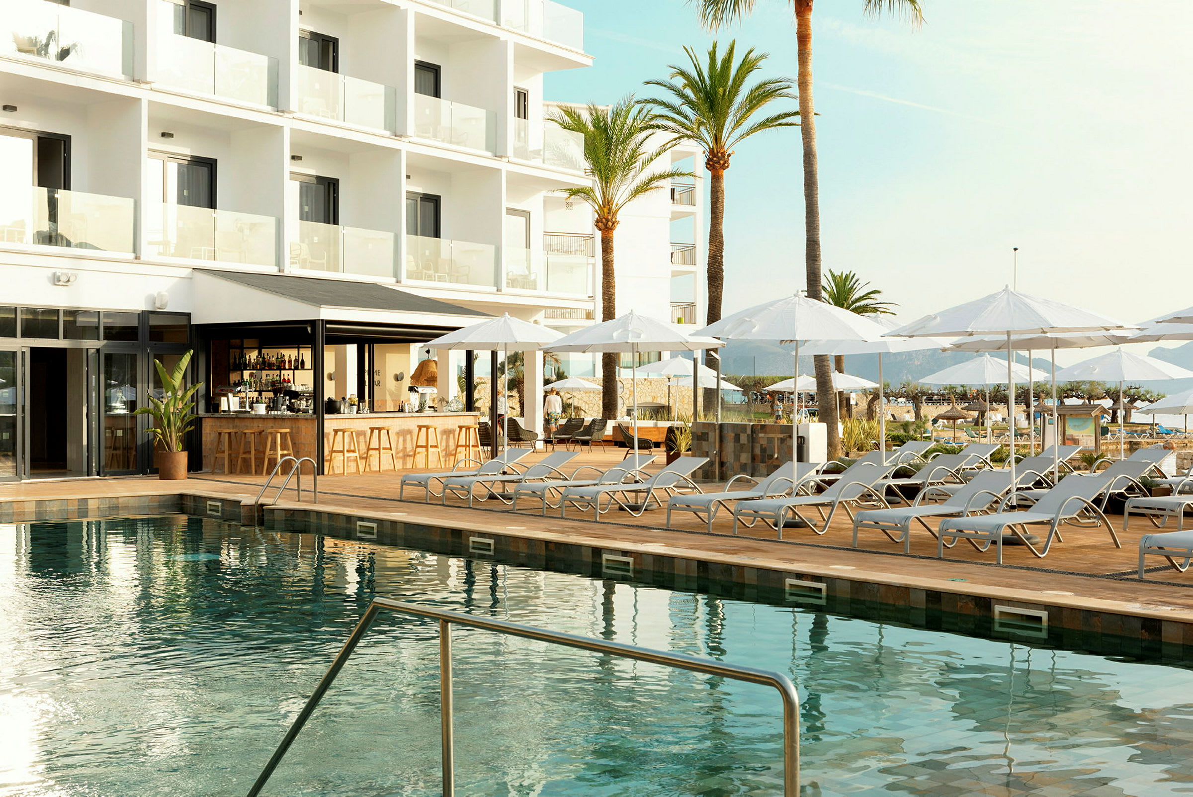 Udendørs pool med liggestole og parasoller ved et moderne hotel. (AI-genereret tekst)