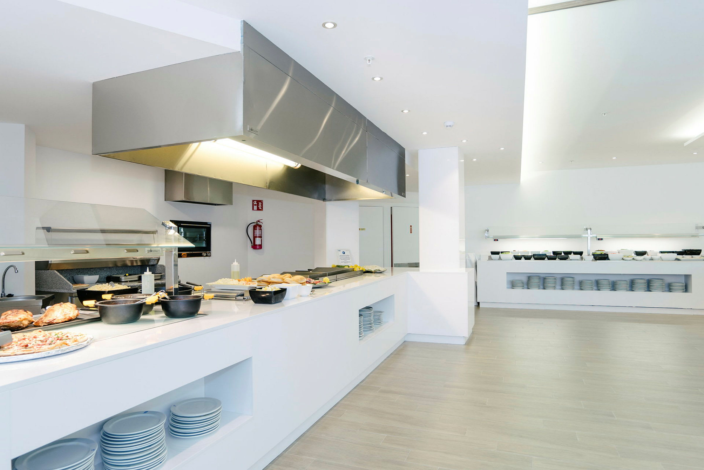 En moderne buffetrestaurant med mad lagt op og tallerkener til rådighed. (AI-genereret tekst)