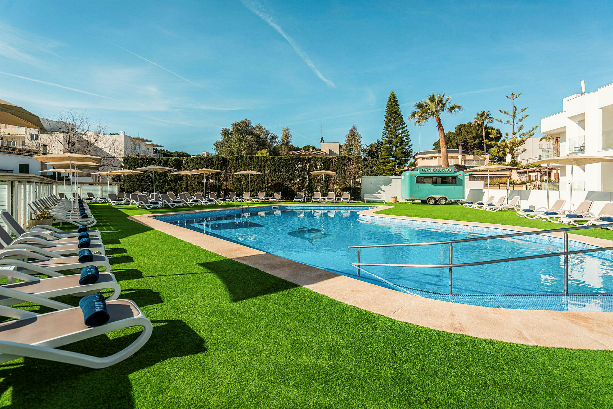 Udendørs swimmingpool med liggestole og grønne omgivelser. (AI-genereret tekst)