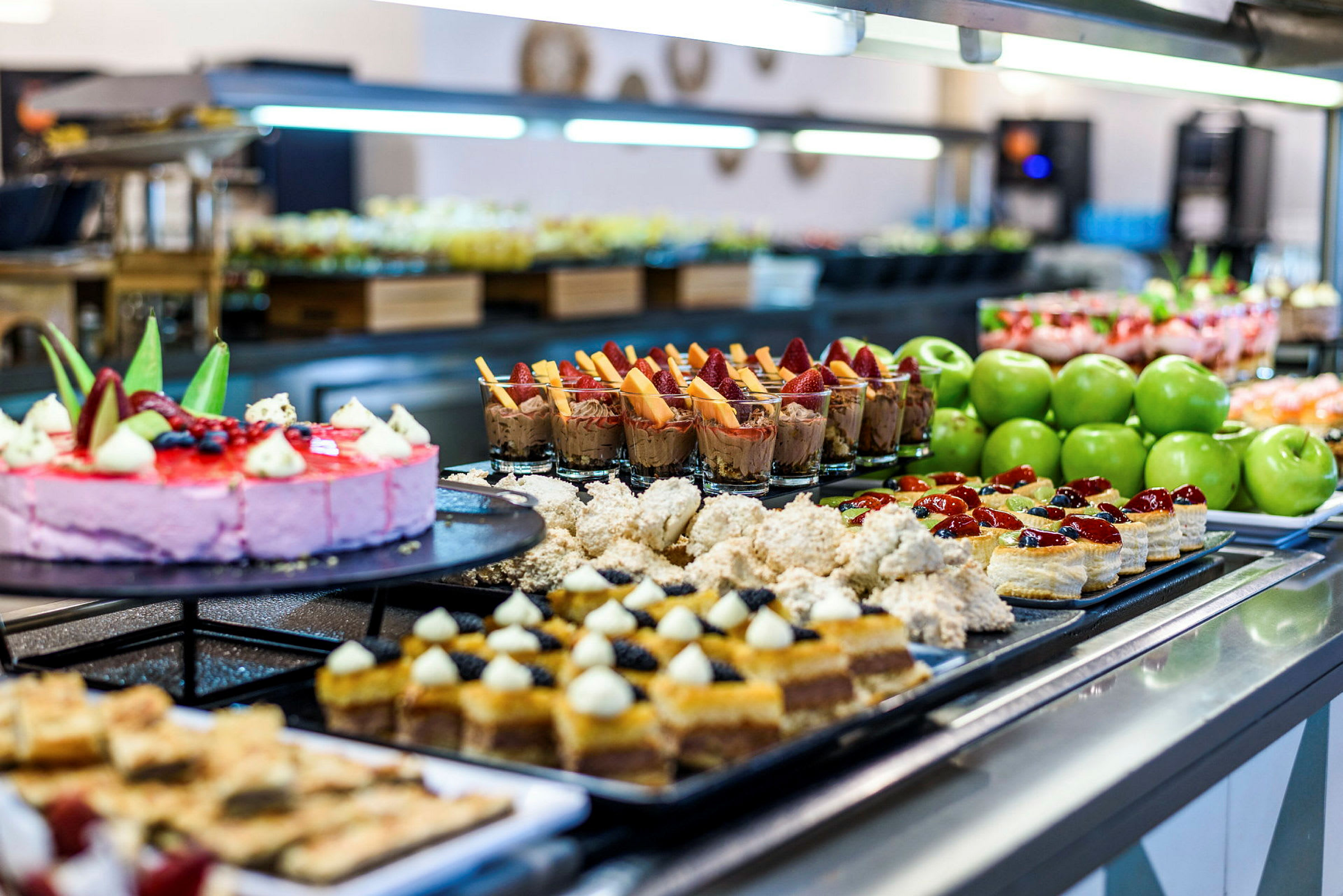 Buffet med forskellige desserter, kager og grønne æbler. (AI-genereret tekst)