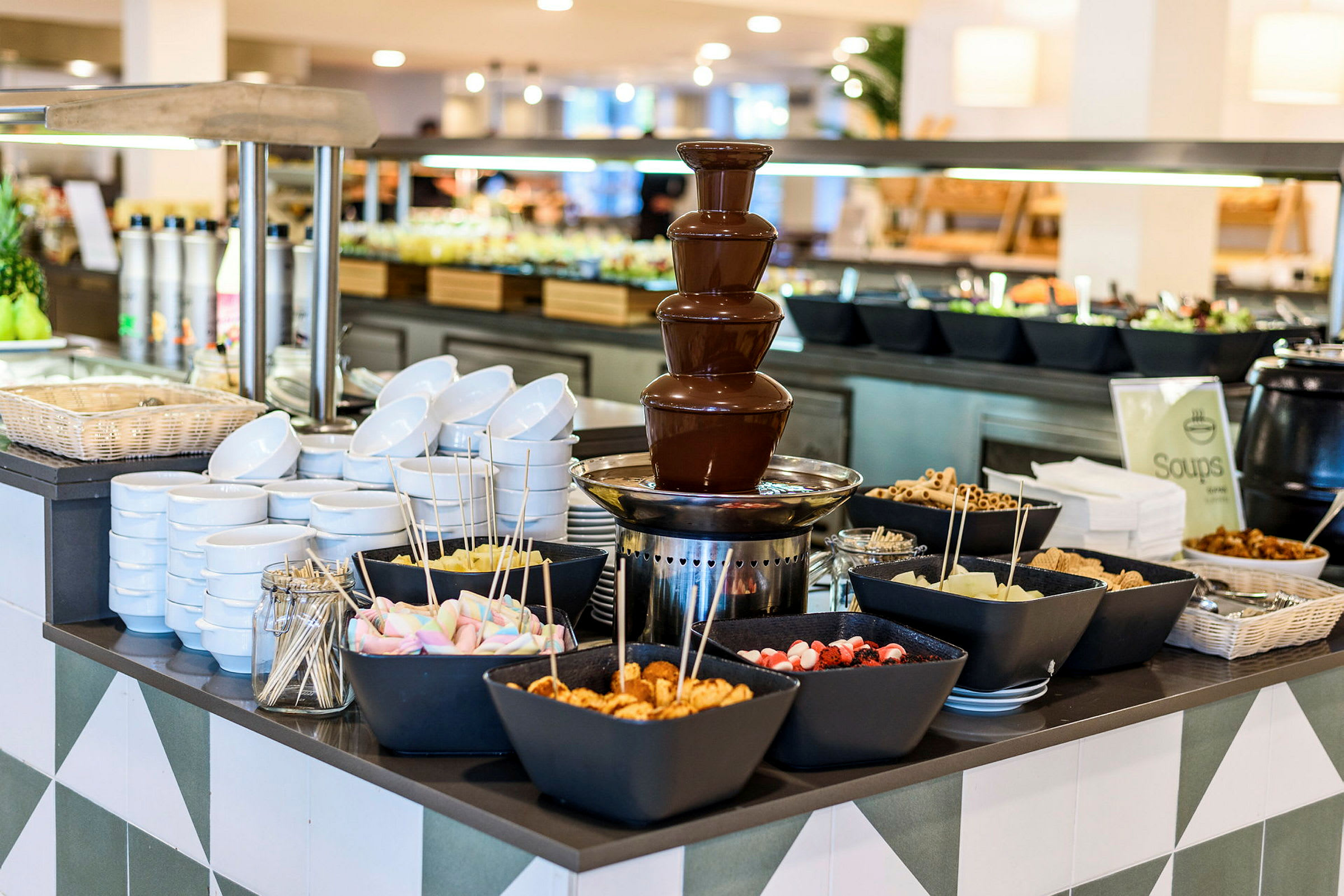 En buffet med en chokoladefontæne og skåle fyldt med forskellige tilbehør. (AI-genereret tekst)