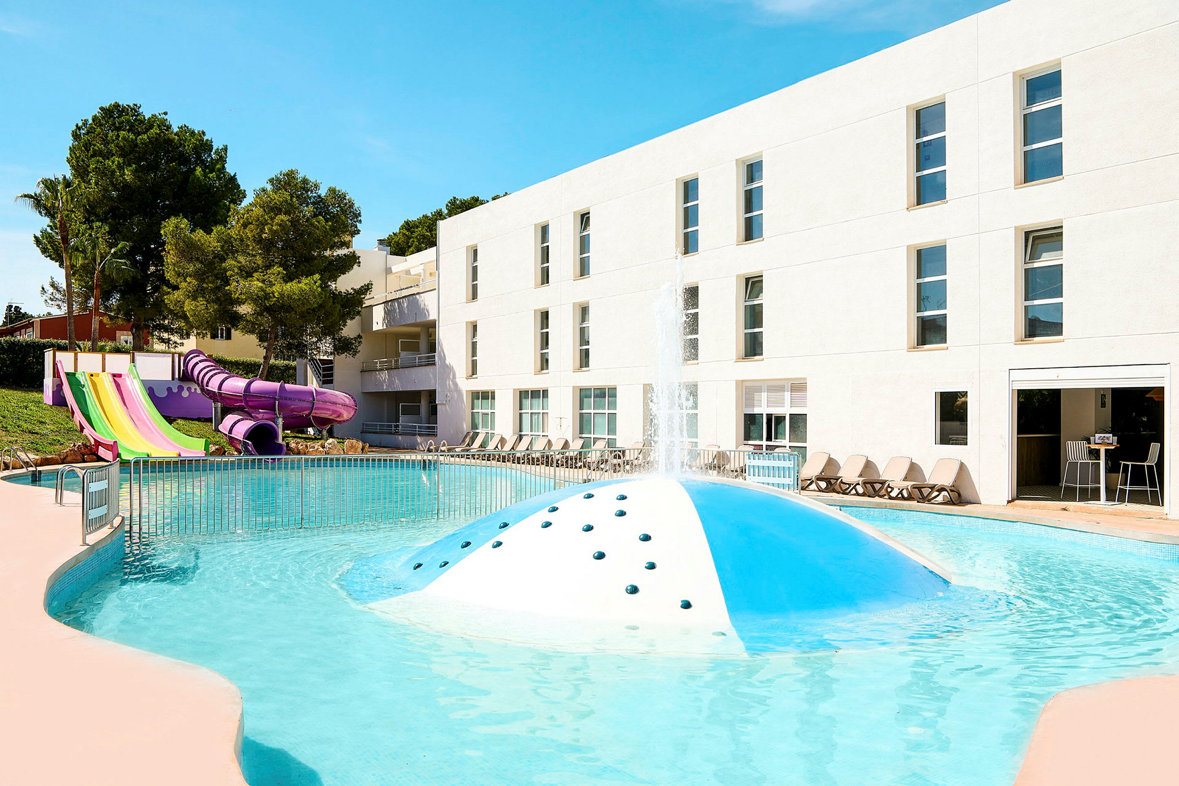 Udendørs swimmingpool med vandrutsjebaner og liggestole omkring. (AI-genereret tekst)