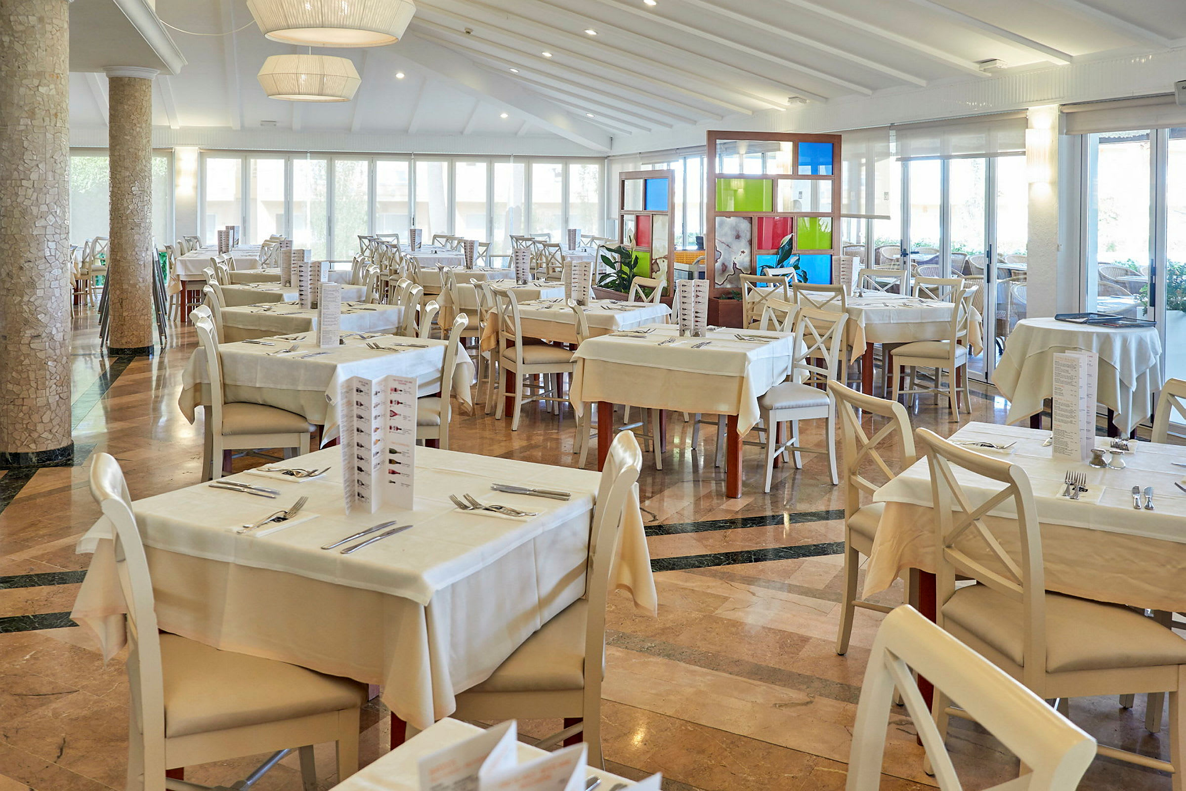 En lys og rummelig restaurant med dækkede borde og stole. (AI-genereret tekst)