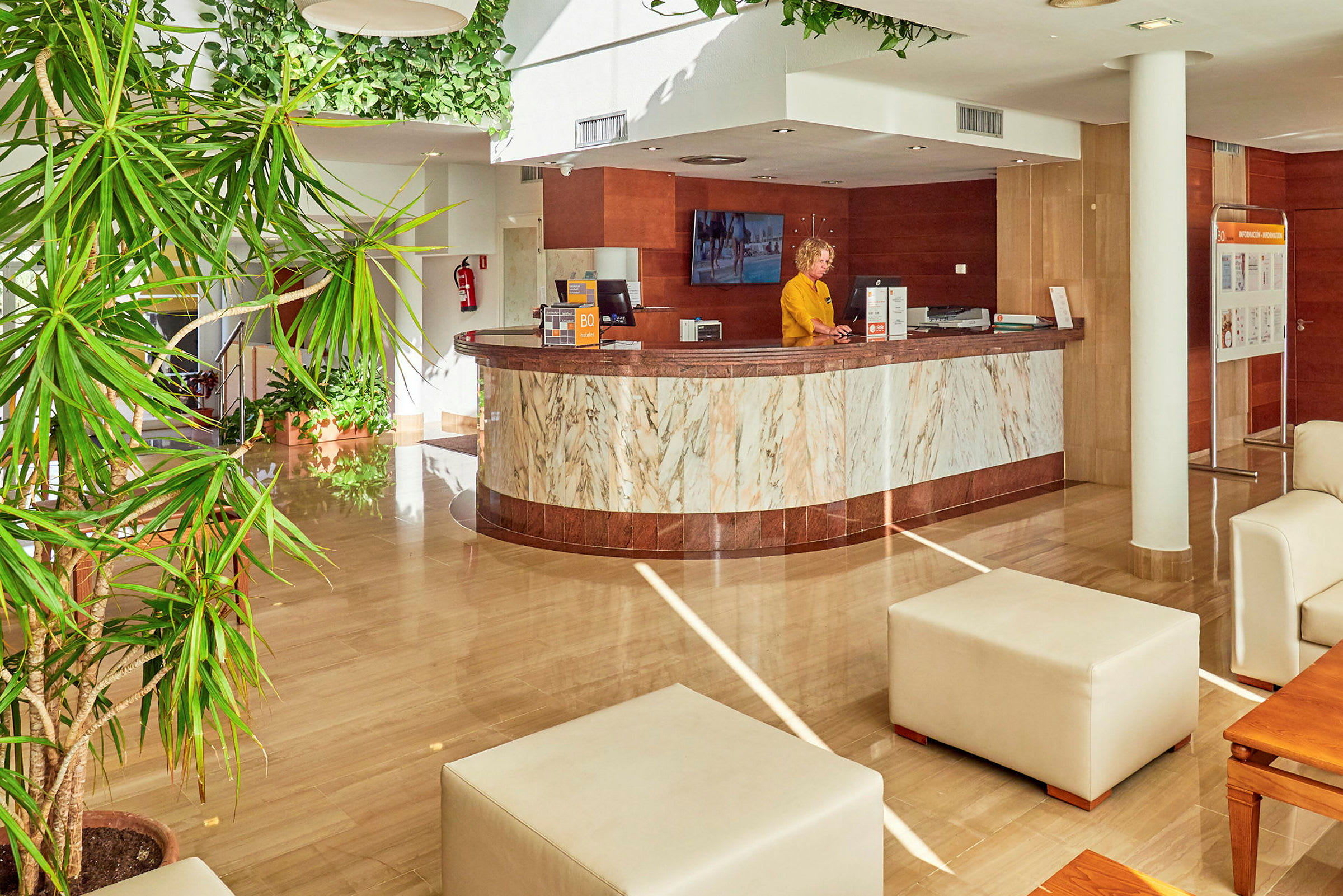 Hotelreception med marmorindretning og grønne planter. (AI-genereret tekst)
