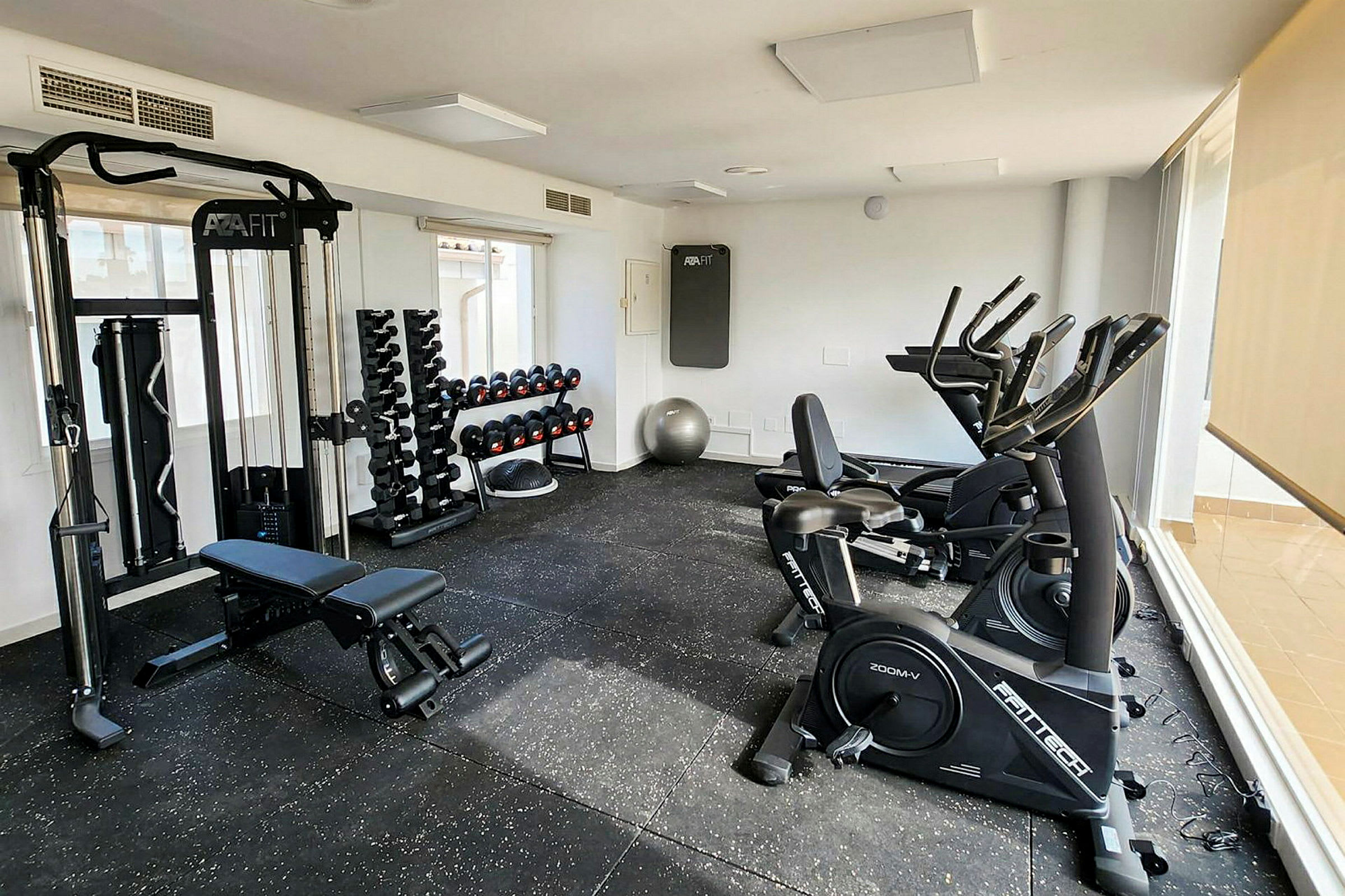 Et gym med træningsudstyr, inklusive træningsmaskiner, håndvægte og bænke. (AI-genereret tekst)