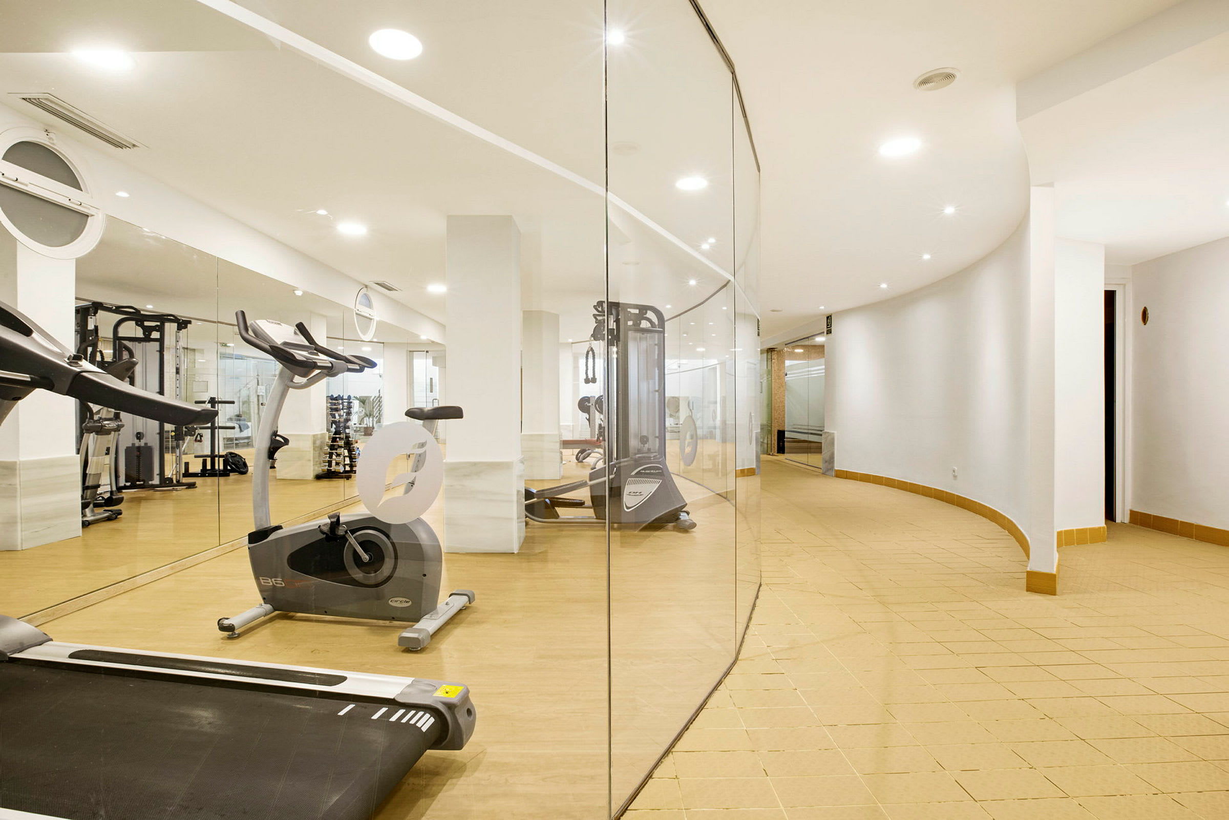 Et fitnesscenter med træningsudstyr og spejlvægge. (AI-genereret tekst)