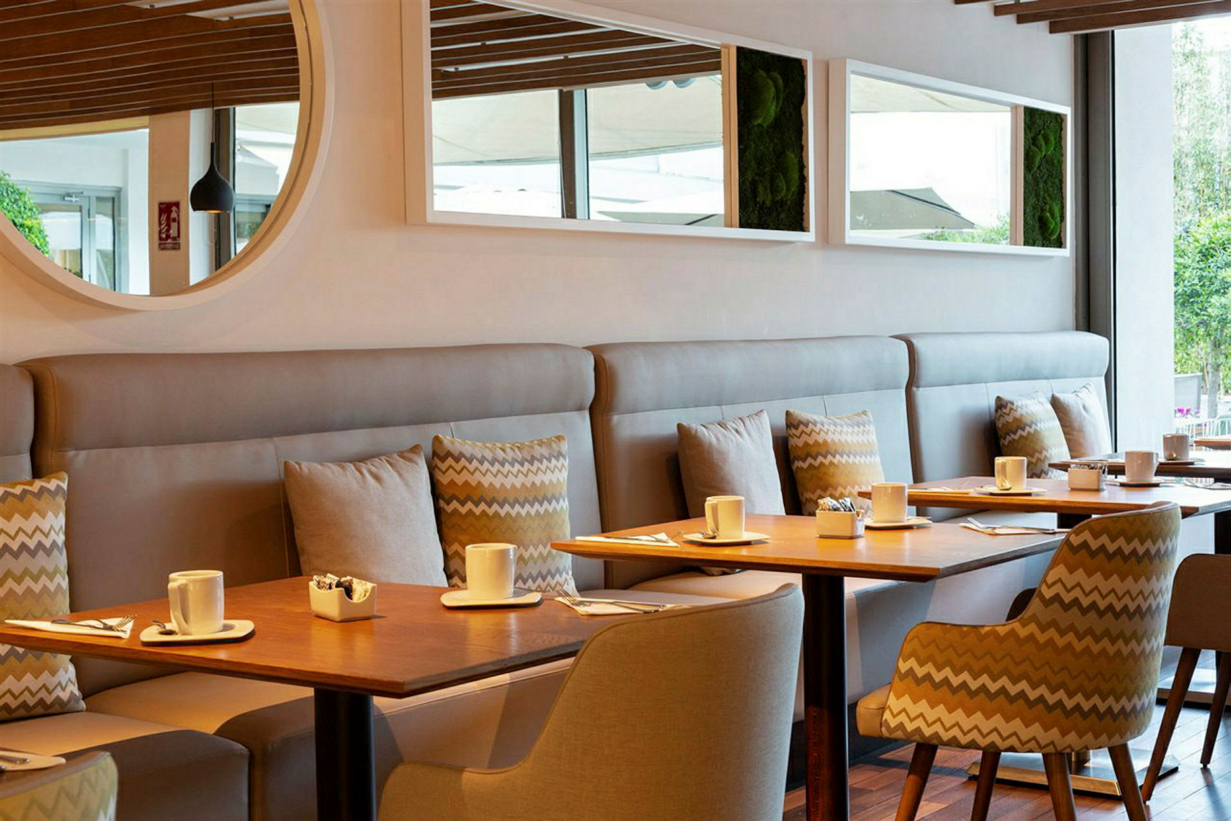 En moderne café med træborde, stole og sofaer. På bordene står kopper og små skåle. (AI-genereret tekst)