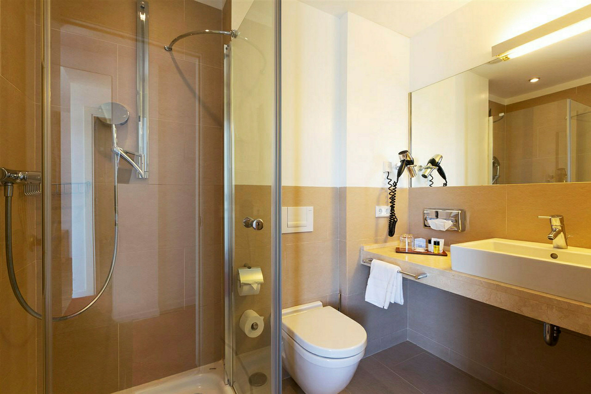 Et skinnende og moderne badeværelse med brusekabine, toilet og håndvask. (AI-genereret tekst)