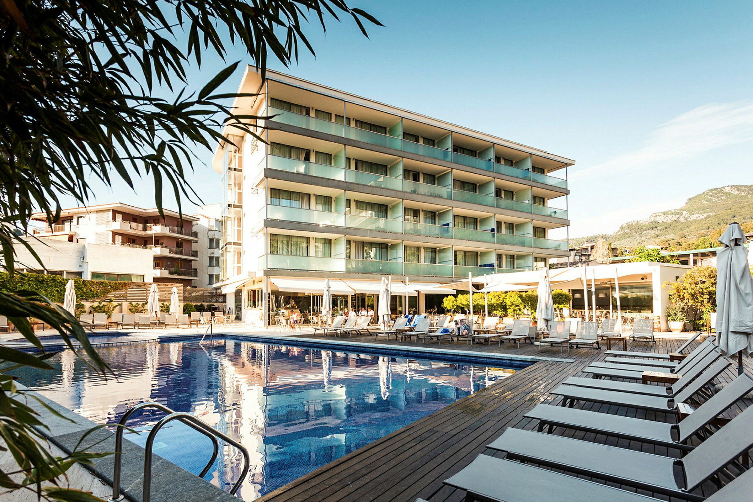 Billede af et hotel med swimmingpool og liggestole udendørs. (AI-genereret tekst)