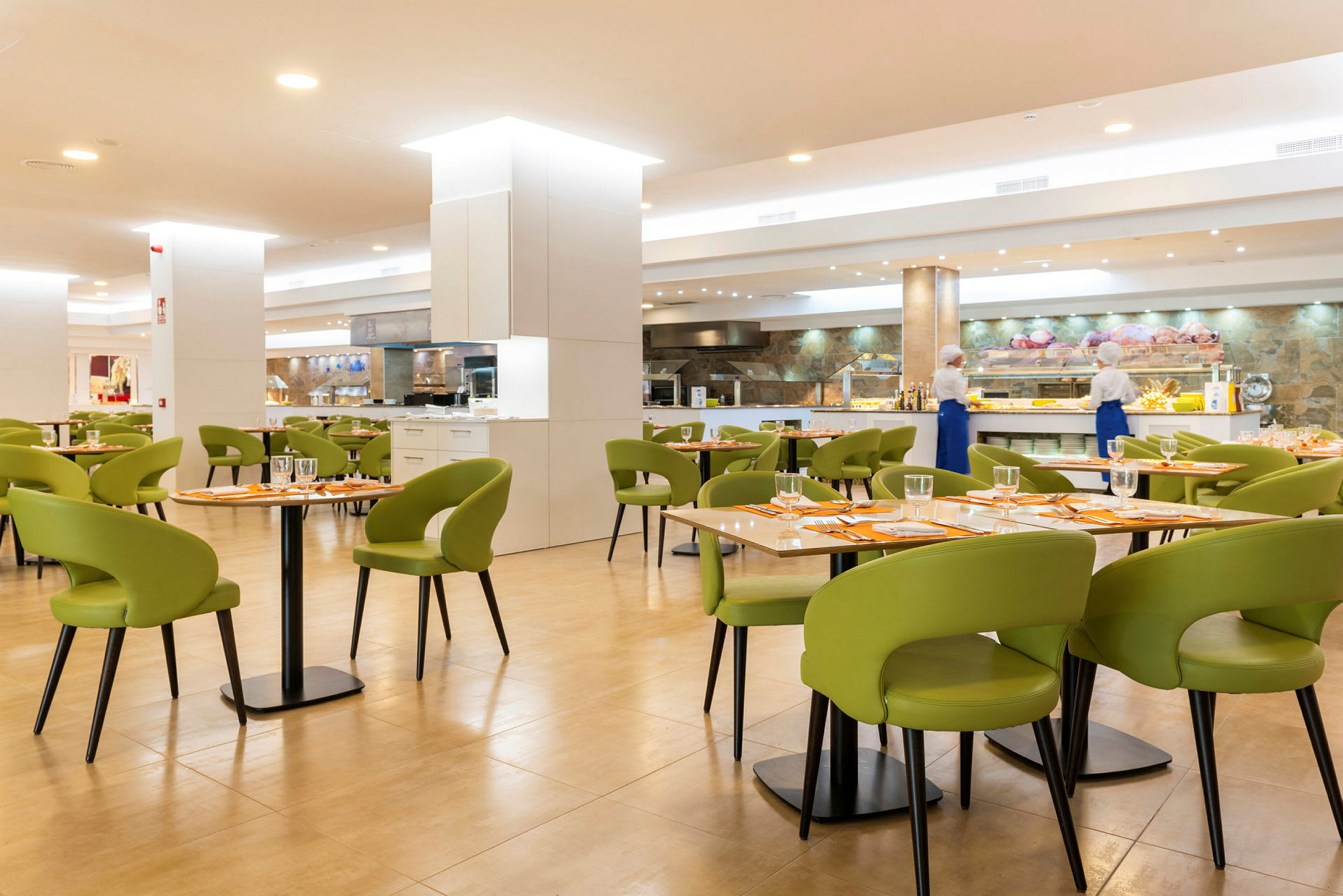 En restaurant med borde med grønne stole og bordopdækning. (AI-genereret tekst)