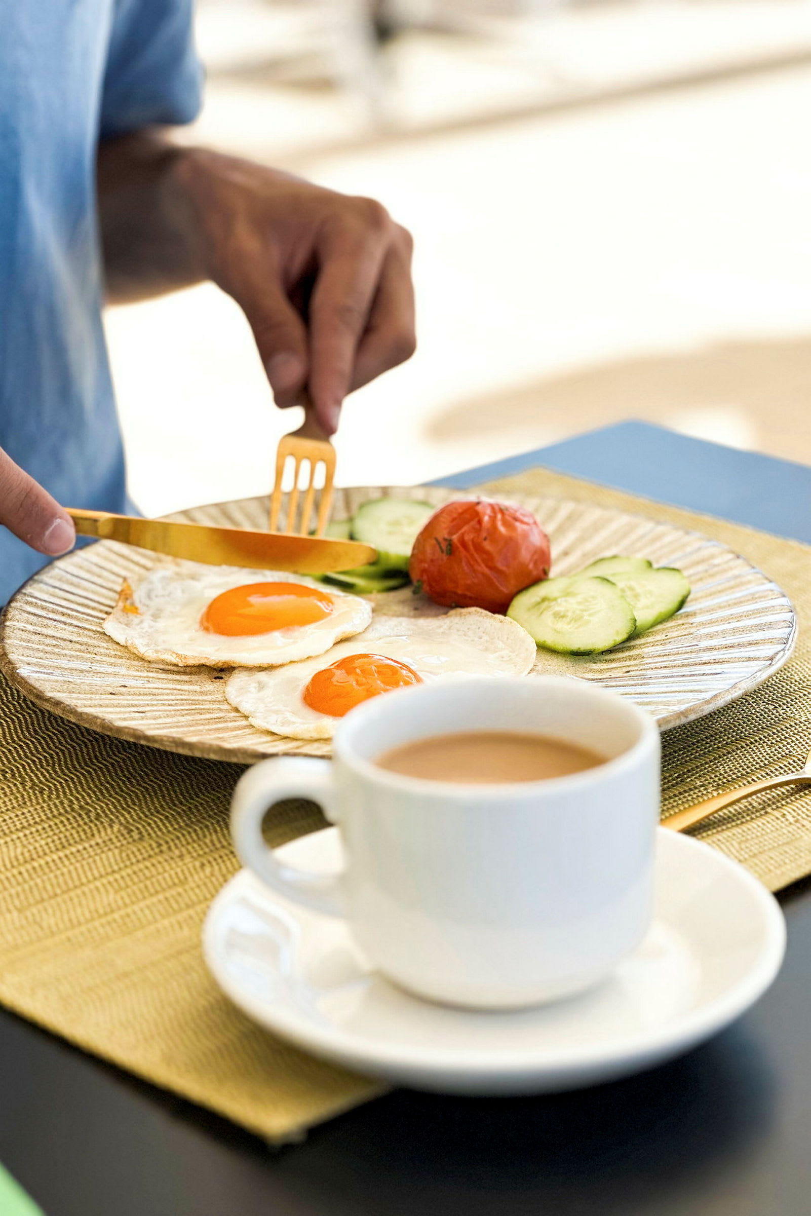 En person spiser morgenmad bestående af spejlæg, tomat, agurkeskiver og kaffe. (AI-genereret tekst)