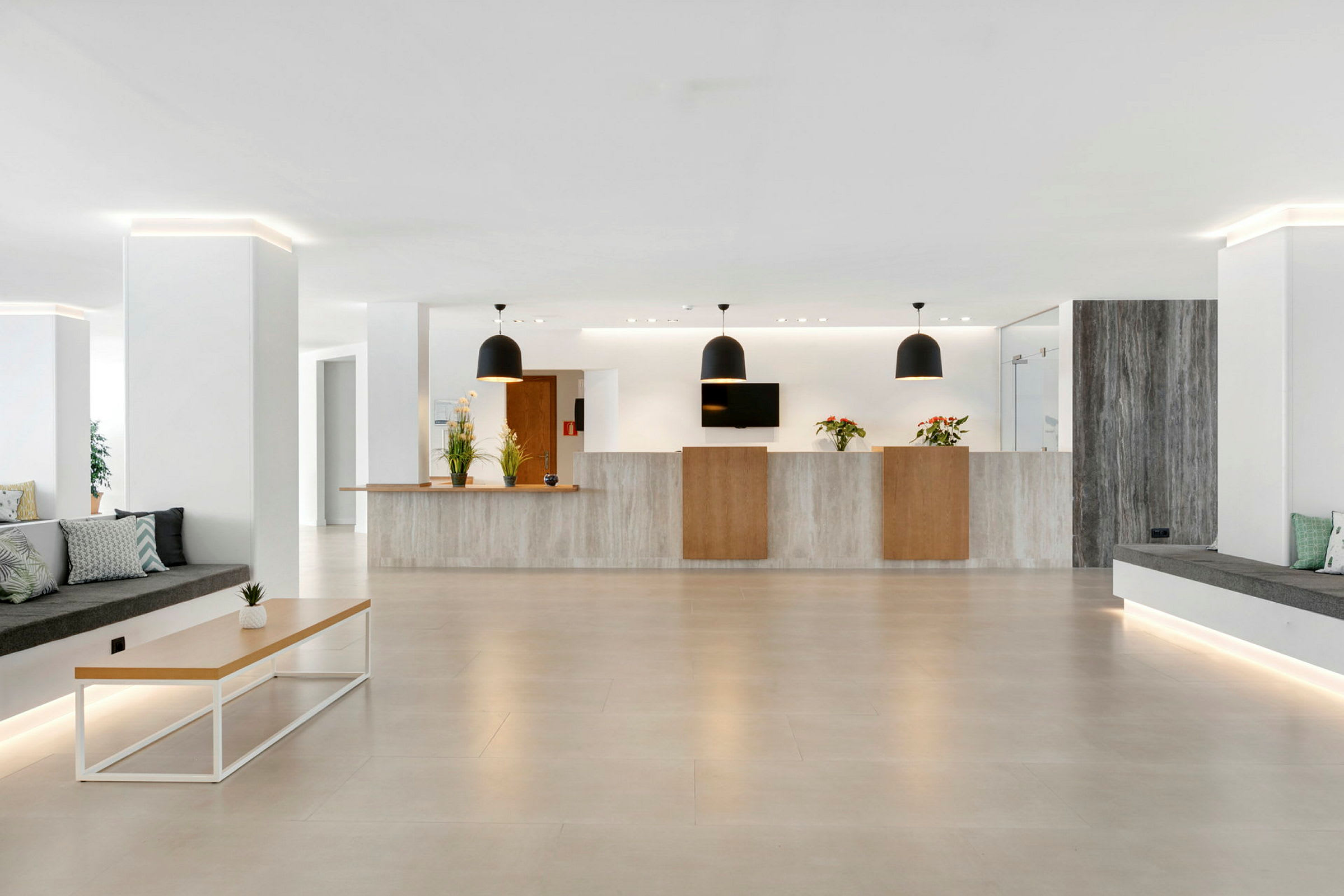Hotellets lobby med receptionsskranke, moderne møbler og planter. (AI-genereret tekst)