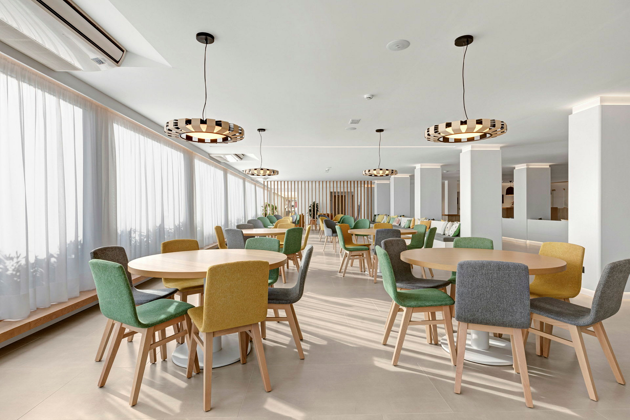 En restaurant med runde borde og stole i forskellige farver. (AI-genereret tekst)