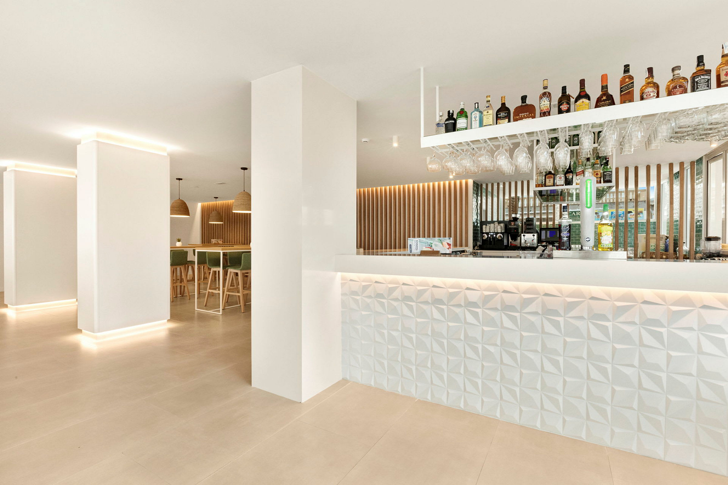Moderne indrettet hotelbar med oplyst disk og hylder med drikkevarer. (AI-genereret tekst)