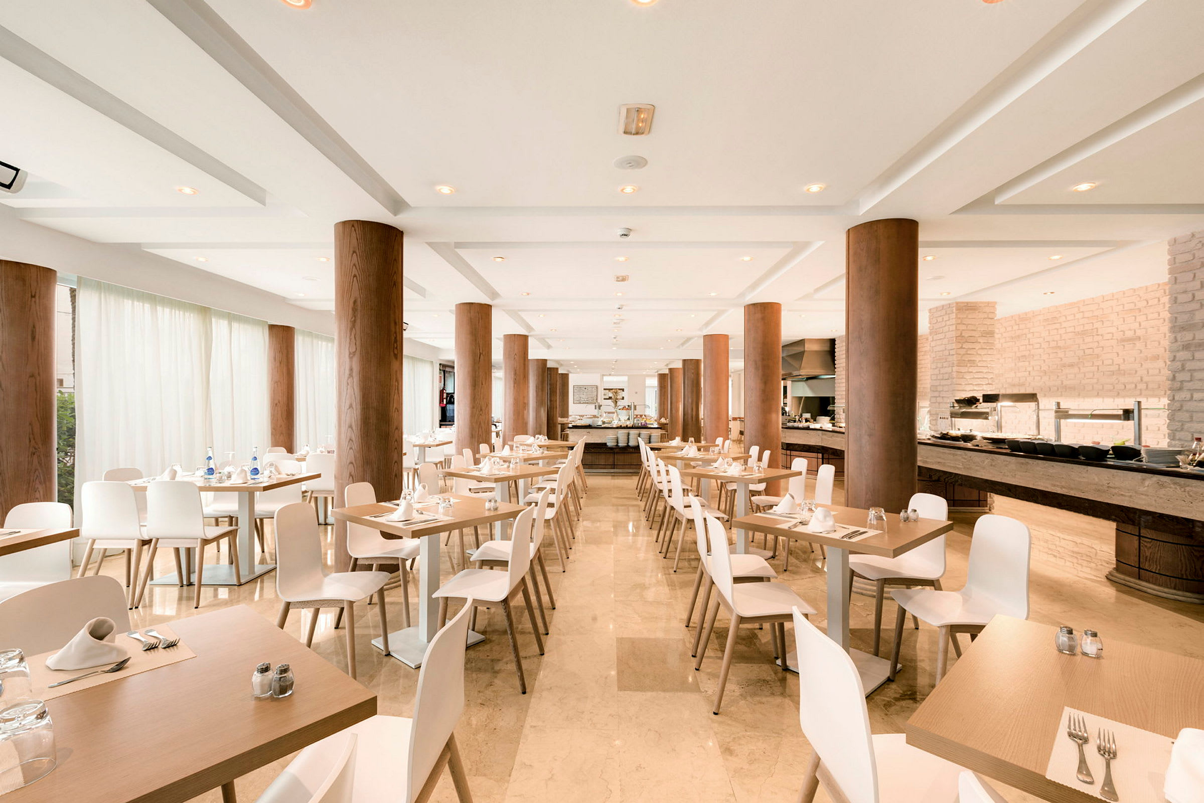 Moderne indrettet restaurant med dækkede borde og store træpiller. (AI-genereret tekst)
